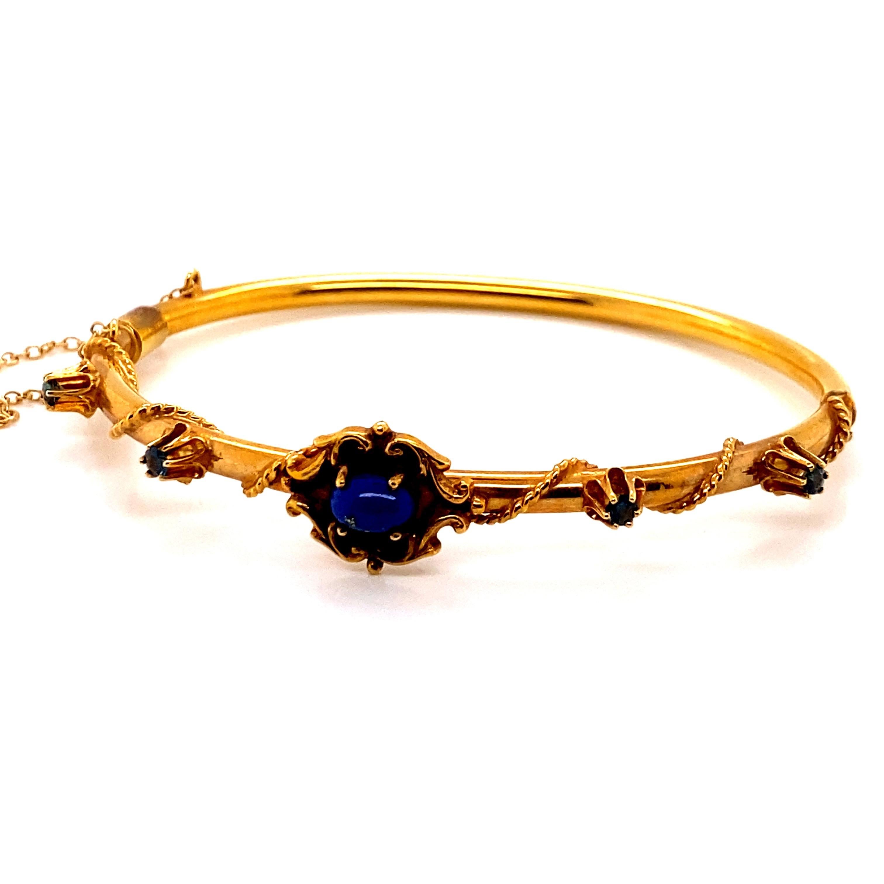 Vintage 14K Yellow Gold Bangle with Lapis and Sapphires - The center stone is Lapis and measures 7 x 4.8mm. There are 4 round sapphires that weigh approximately .40ct total weight. The width of the bangle is 3.5mm. The bracelet weighs 12.72 grams.
