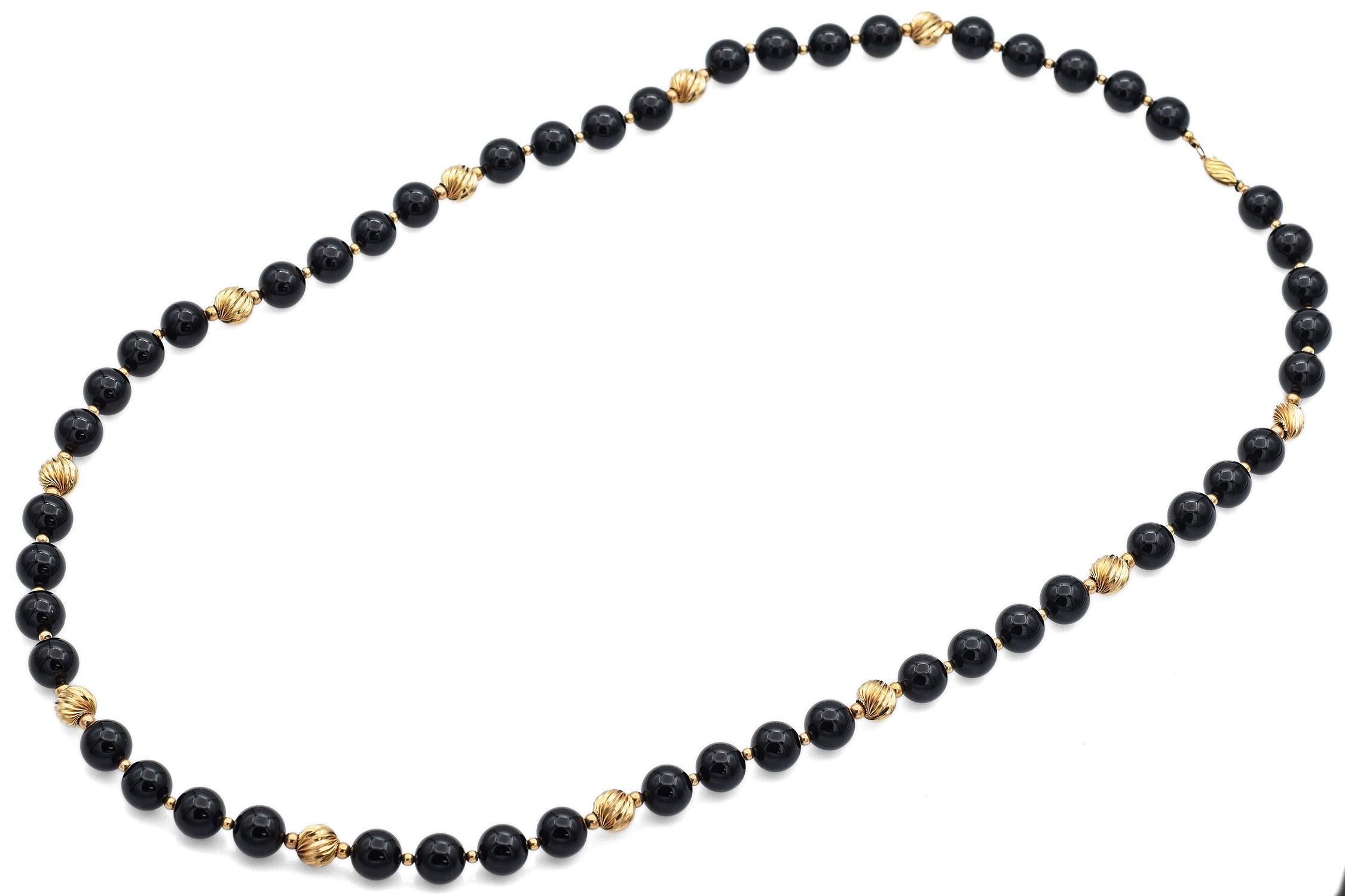 Vintage Strang Halskette aus polierten runden schwarzen Onyx-Perlen, akzentuiert mit gerippten 14k Gelbgold Perlen im gesamten. Die lange Länge bietet Vielseitigkeit für Einzel- oder Doppelträger, mit einem klassischen Kontrast aus tiefem Schwarz