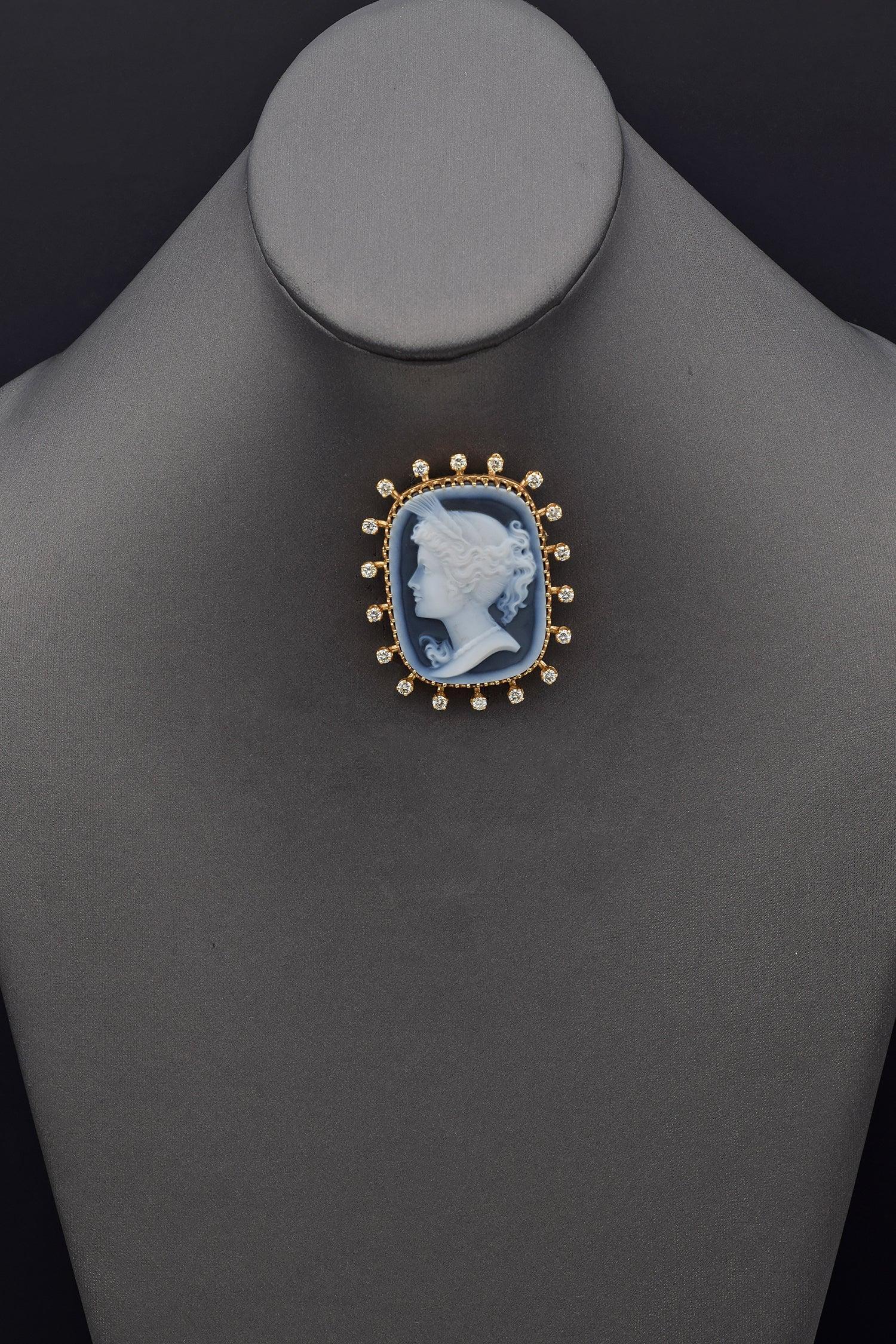 This elegant 14K yellow gold brooch showcases a finely carved blue agate cameo depicting a classical profile. The cameo is framed by a series of round white diamonds enhancing the brooch's refined appearance.

Weight: 21.7 Grams
Stone: Blue Cameo