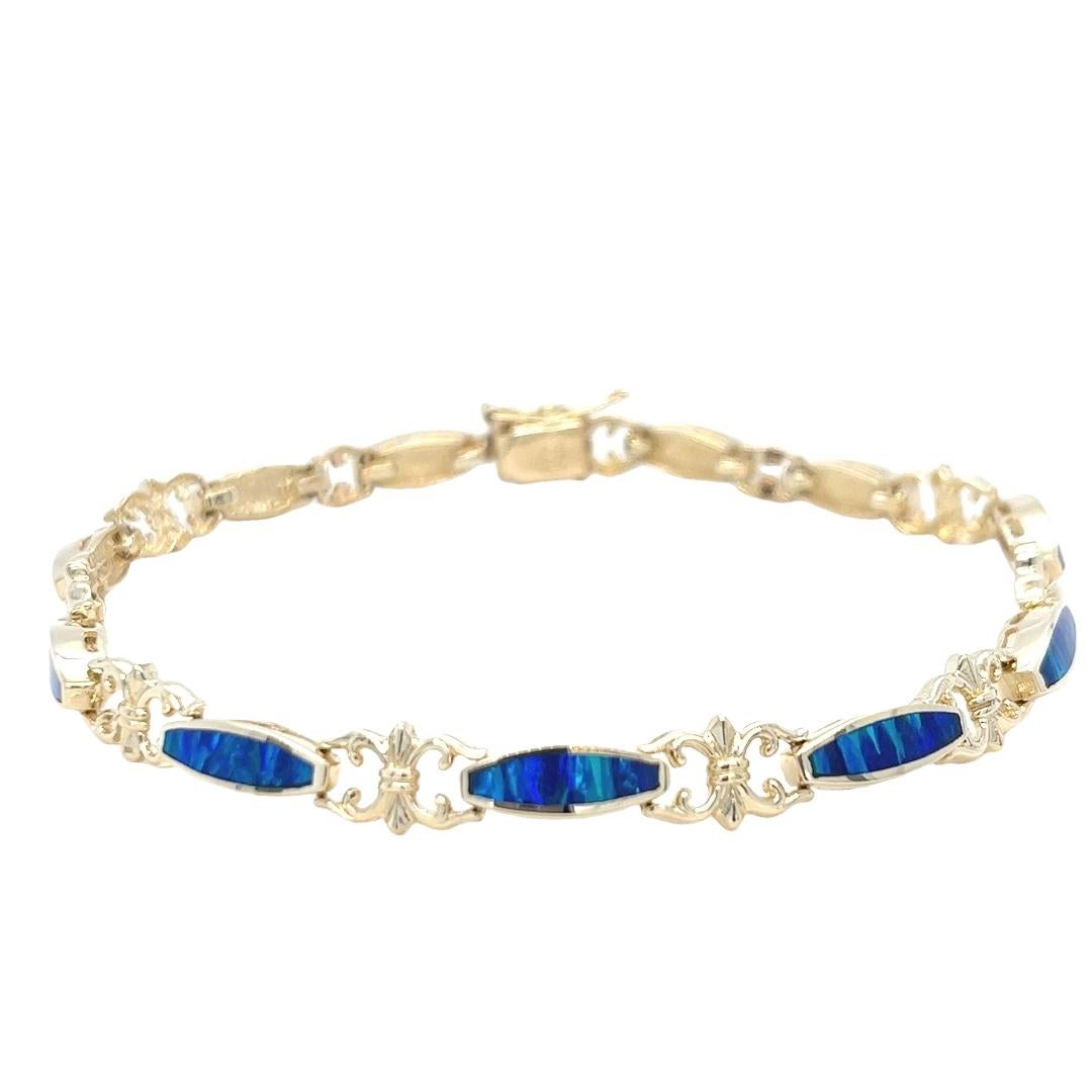 Esta llamativa pulsera vintage está elaborada en oro amarillo de 14 quilates y luce una vibrante incrustación de ópalo azul y verde. Cada segmento de ópalo está engastado con precisión en los eslabones de oro, creando un mosaico fluido e iridiscente