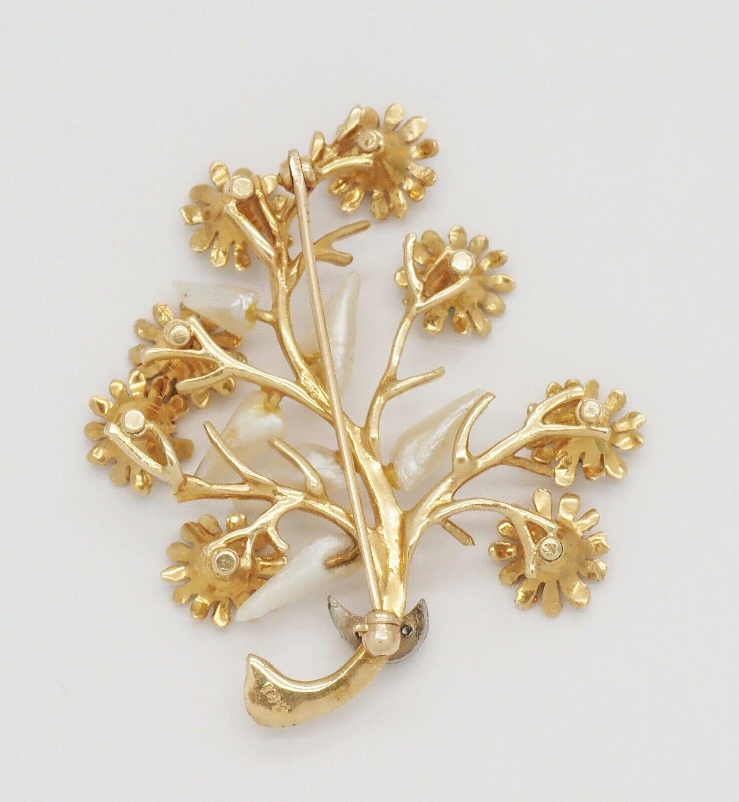 Questa incantevole spilla vintage a 14 carati presenta uno stravagante disegno di un albero floreale, realizzato in caldo oro giallo. Ogni fiore sbocciato è incastonato con gemme vibranti come il rubino, lo smeraldo e lo zaffiro, per offrire una