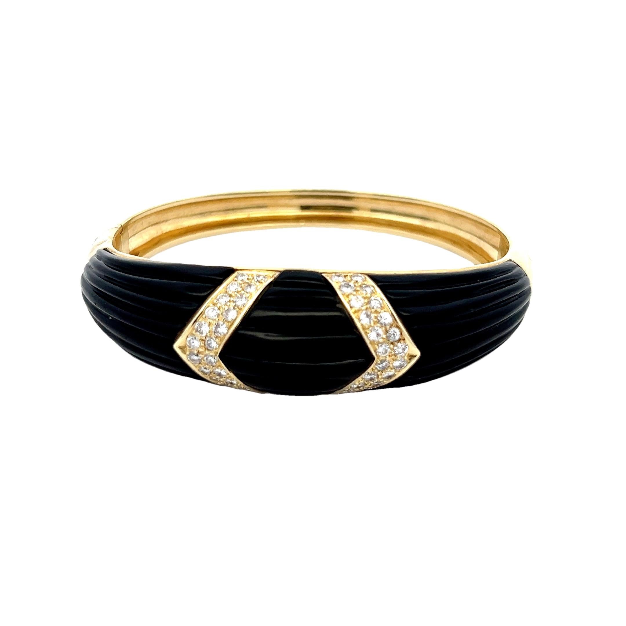 Sleek and sculptural, this vintage 14K yellow gold bangle bracelet is a bold statement piece. Featuring a ribbed carved onyx inlay in deep jet black, the design is accented with two geometric panels of brilliant round-cut diamonds totaling
