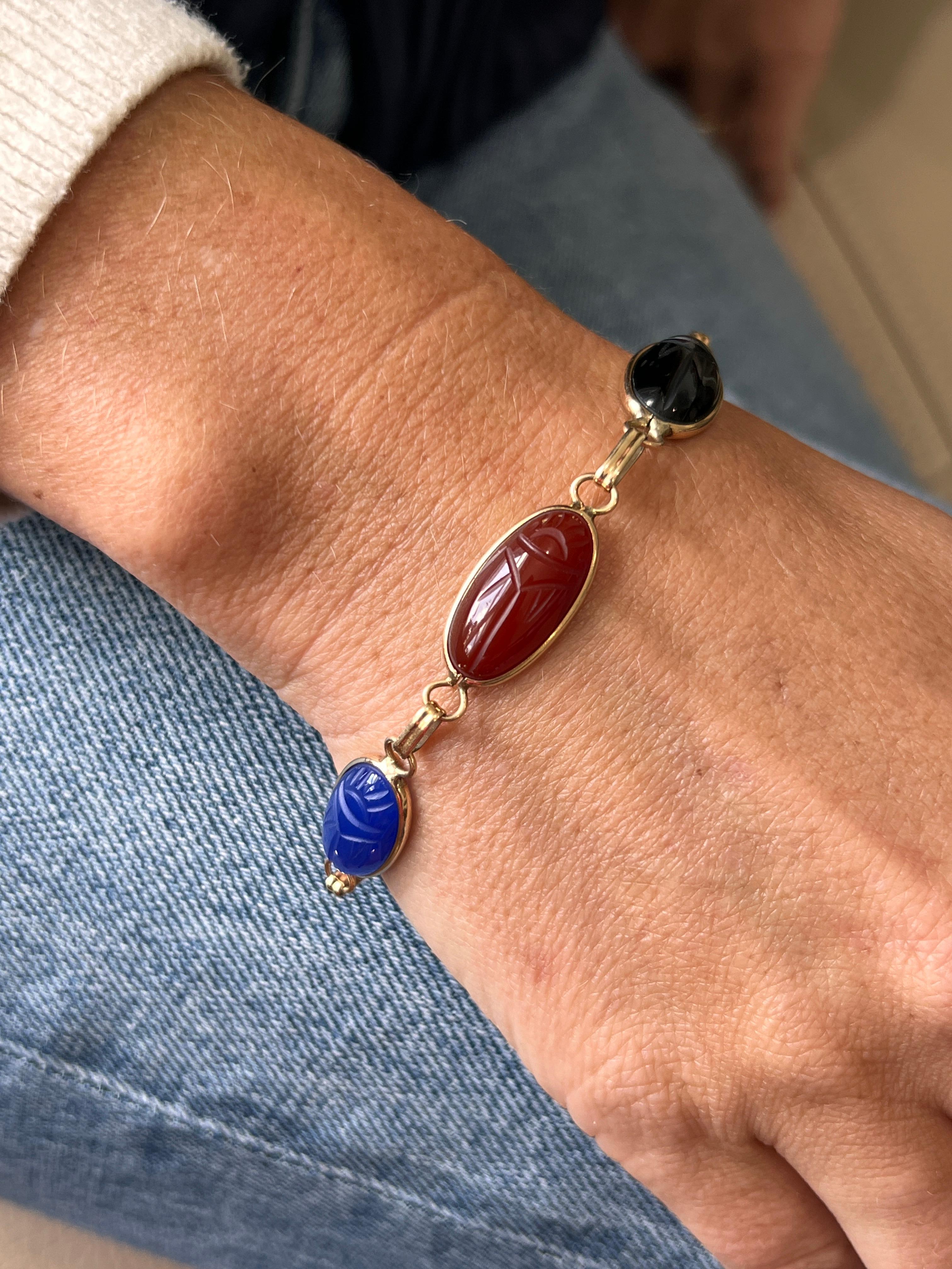Ce bracelet vintage des années 1970 met en valeur cinq pierres précieuses scarabées magnifiquement sculptées, serties dans de chaleureux chatons en or jaune 14 carats. Le motif du scarabée de l'Égypte ancienne, qui symbolise la renaissance et la