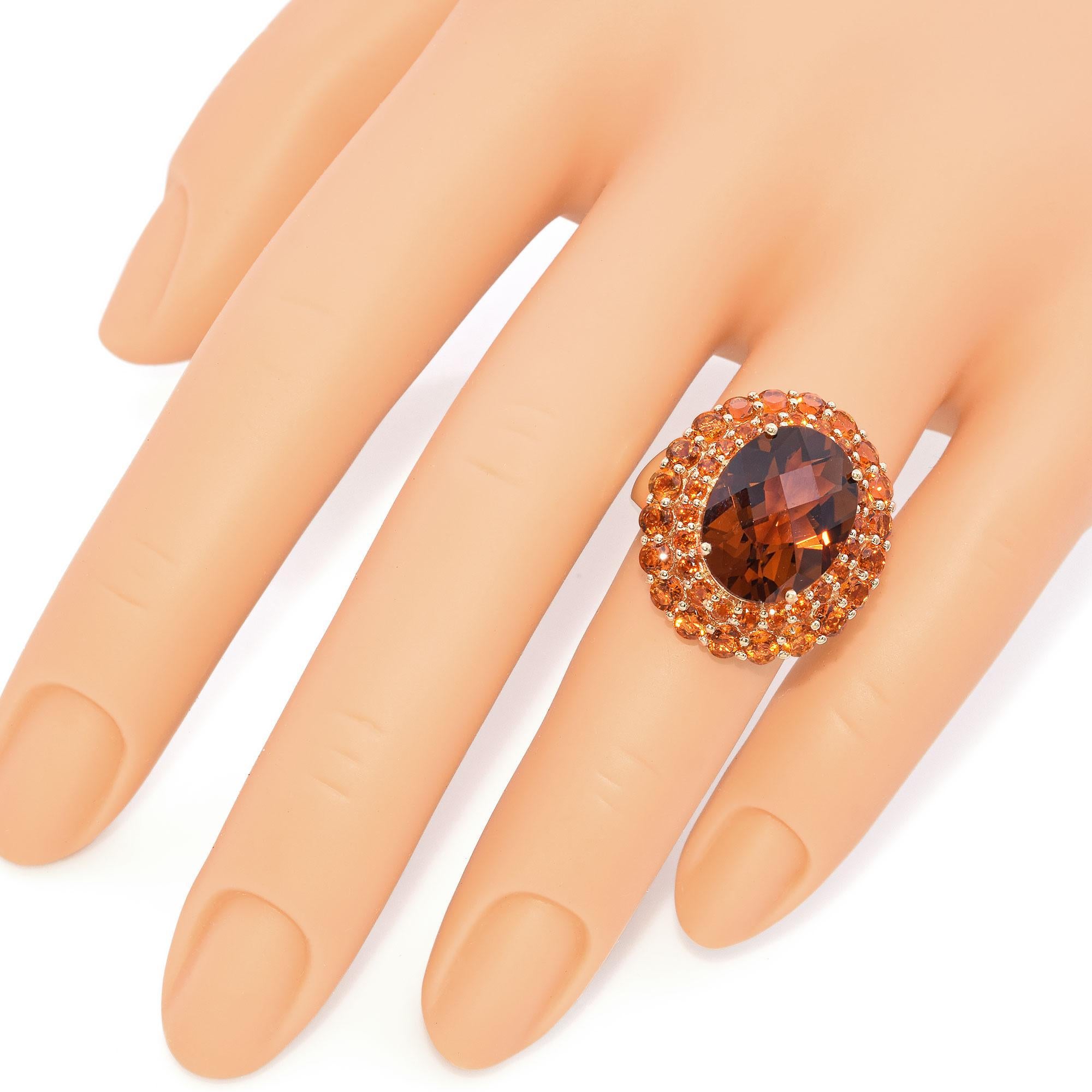 Cette magnifique bague est ornée d'une grande citrine ovale en son centre, entourée d'un halo de citrines rondes plus légères. Les teintes orange vibrantes de la citrine sont complétées par les tons riches et ardents des citrines plus légères,