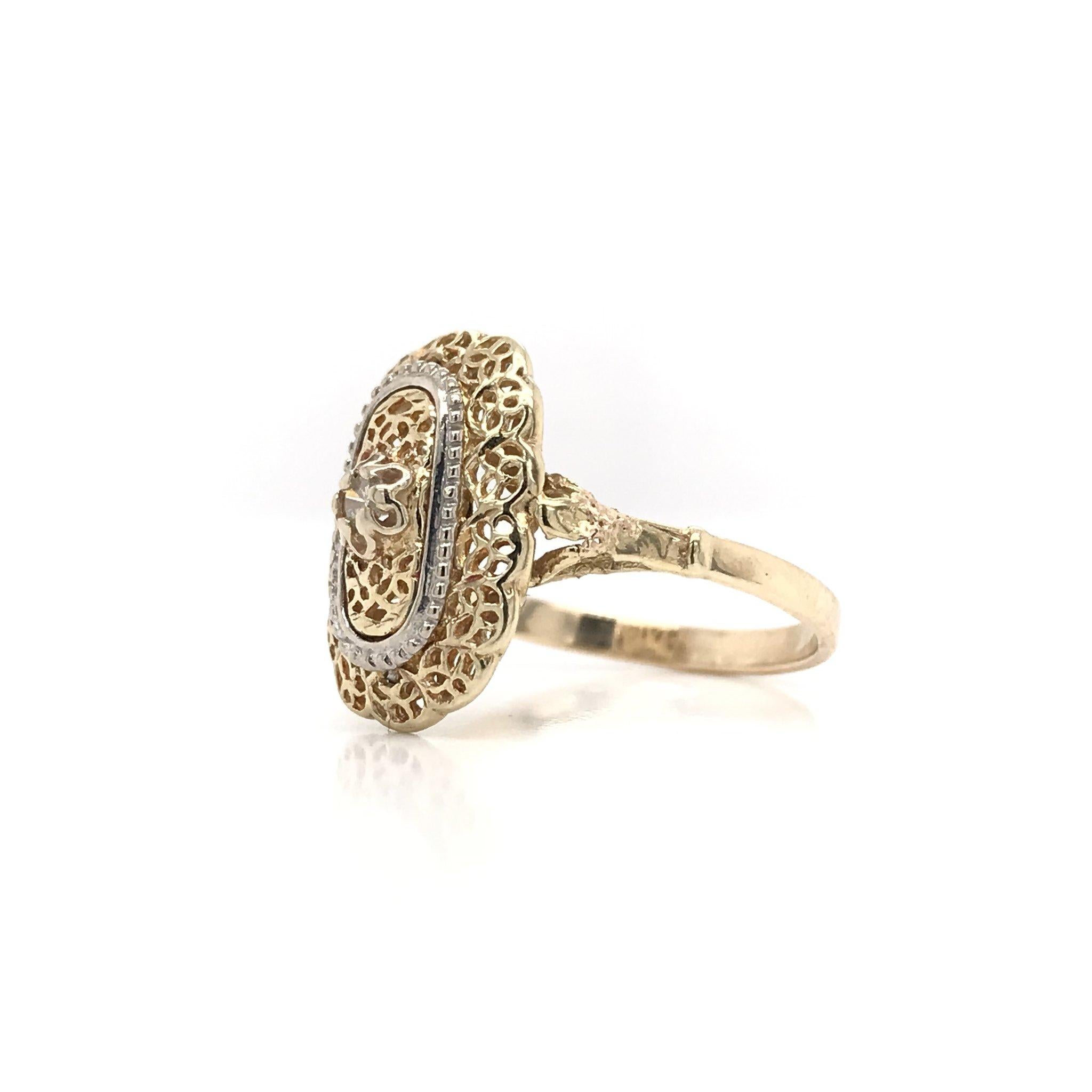 This ring was crafted sometime during the Mid Century design period ( 1940-1960 ). The setting is 14k yellow gold and features 14k white gold accents as well as a tiny center diamond. The ring features a scalloped lace motif along with filigreed