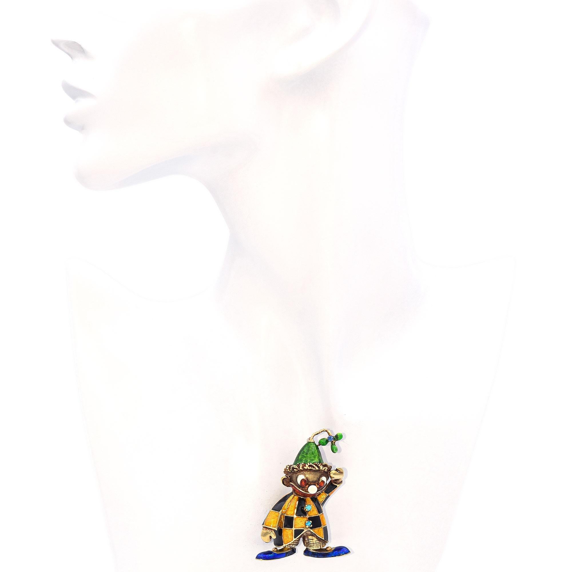 Diese skurrile Brosche ist eine lebendige Darstellung eines Harlekin-Clowns, gefertigt aus 14-karätigem Gold mit leuchtenden Emaille-Details. Die Figur trägt ein klassisch kariertes Kostüm aus abwechselnd goldgelber und tiefschwarzer Emaille, das