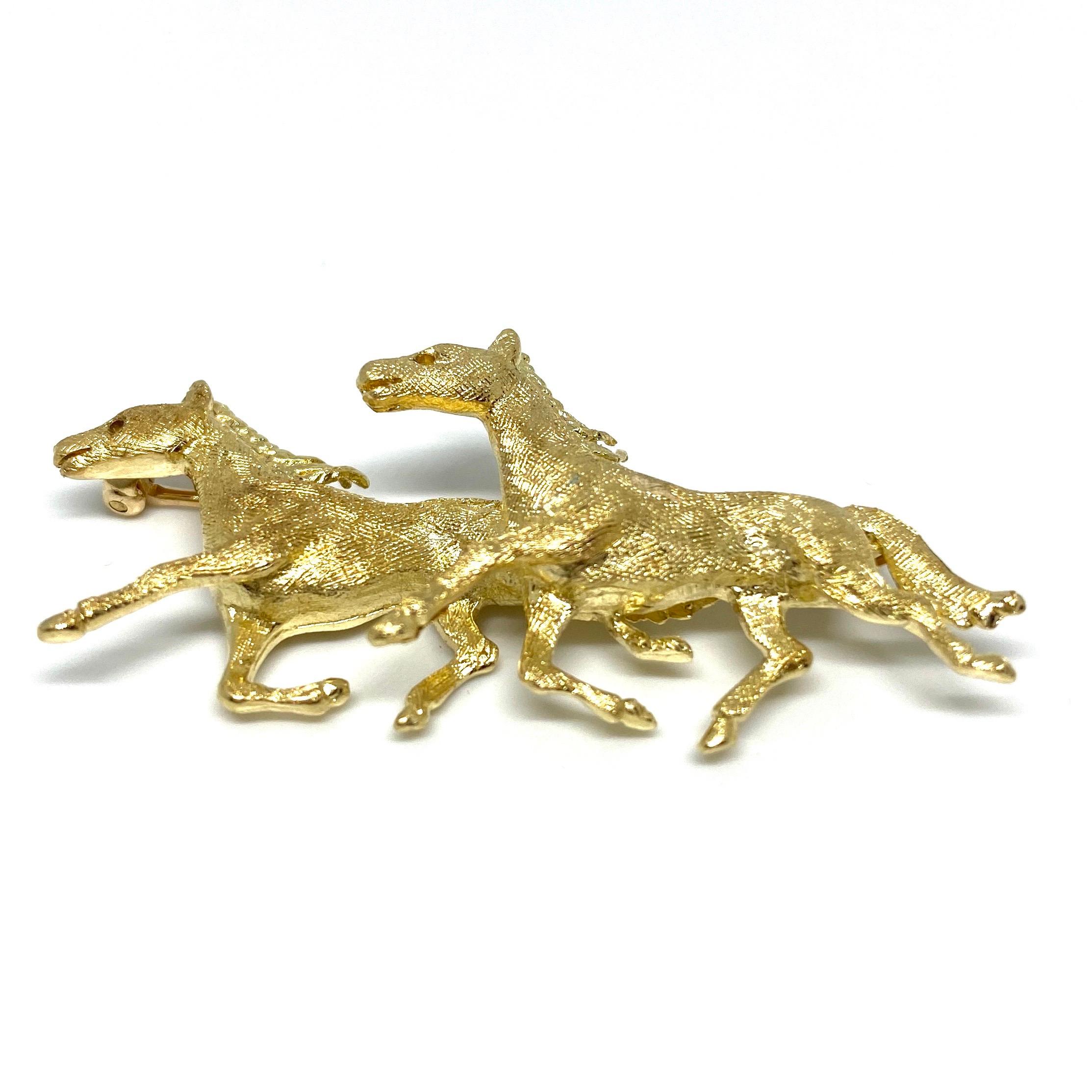 Crafted in 14k yellow gold, the pin features two horses in motion. Satin finish adds extra shine to this beautiful piece. 
Measurements:
2” W x 7/8” H x 3/8” D
Weight: 7.6 grams
Condition: excellent