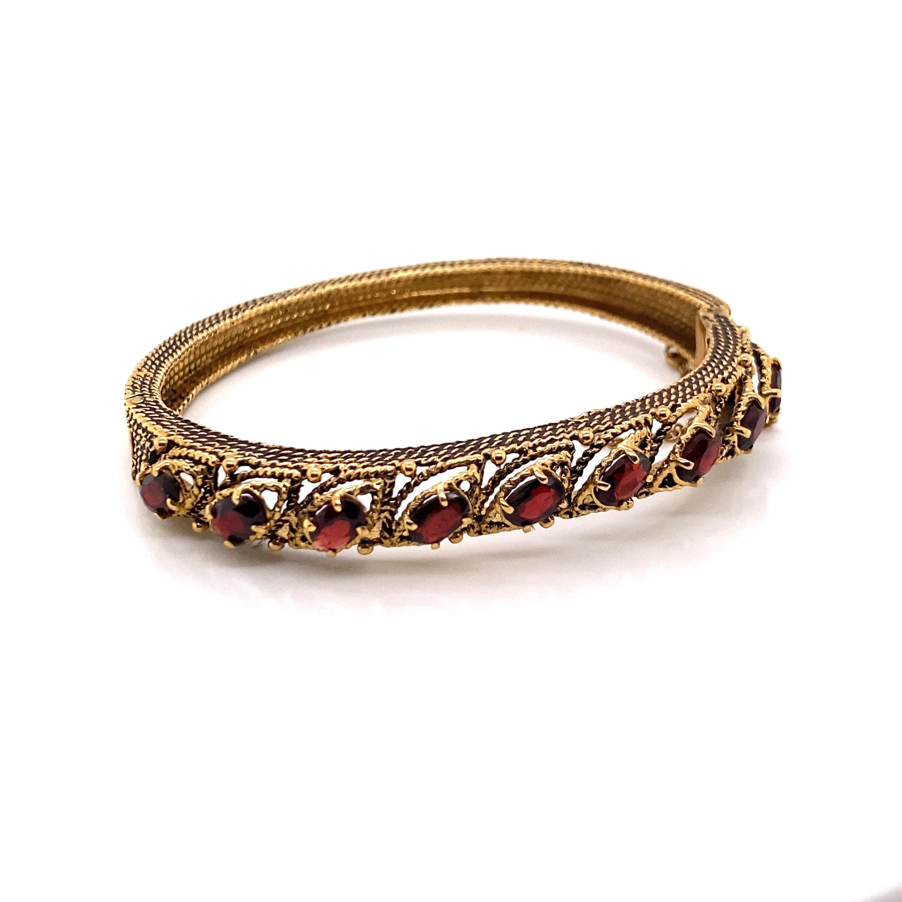 Vintage 14K Yellow Gold Garnet Bangle Bracelet - The bracelet contains 9 oval garnets that measure 6 x 4mm. The width of the bangle is 8.5mm and tapers down to 5mm and has oxidation on the side. The bracelet weighs 23.44 grams.