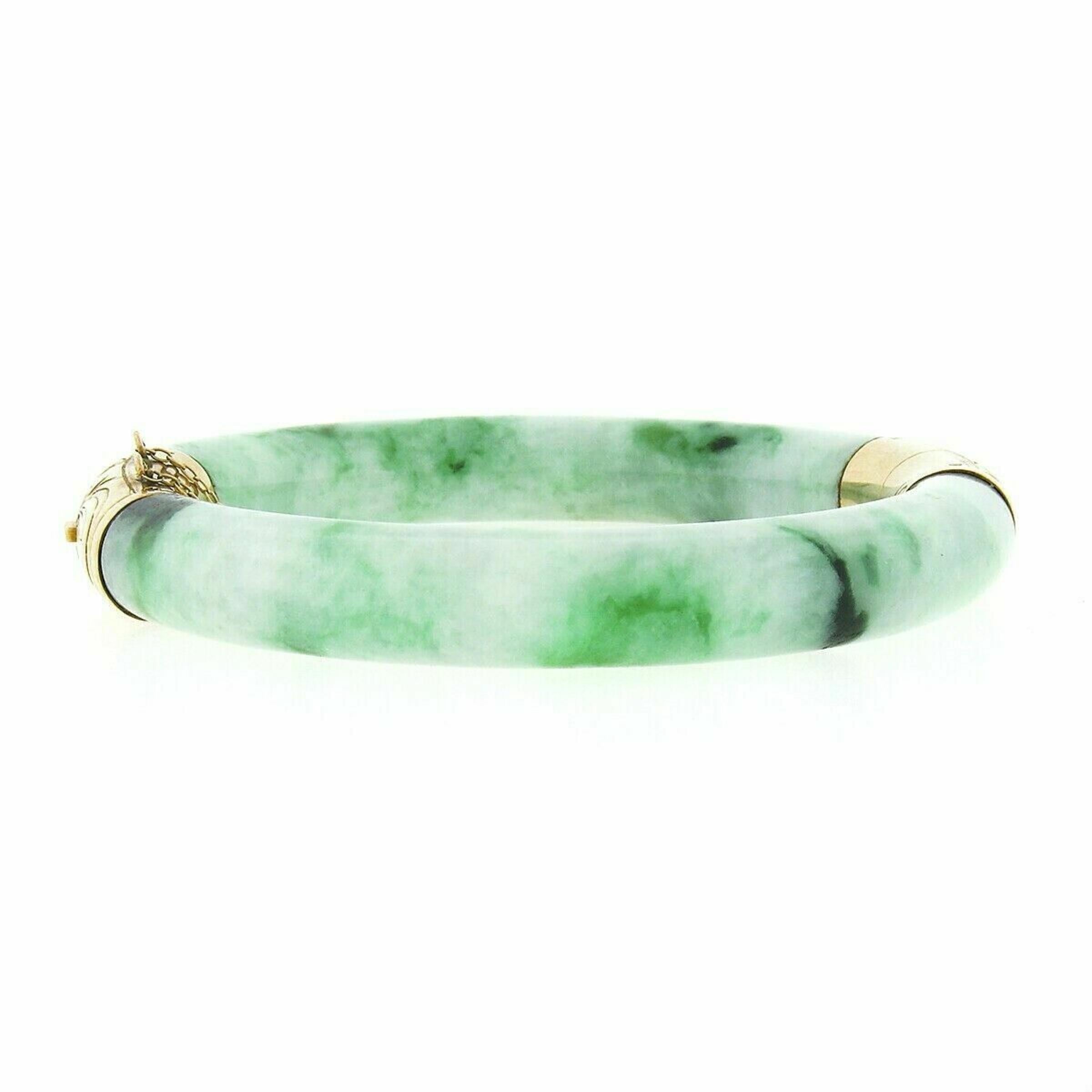 This gorgeous vintage bracelet was crafted from solid 14k yellow gold and features two arc shaped jade stones with a mottled green color. Those curved green jades are held together by gold end caps which are etched with beautiful floral motifs. This