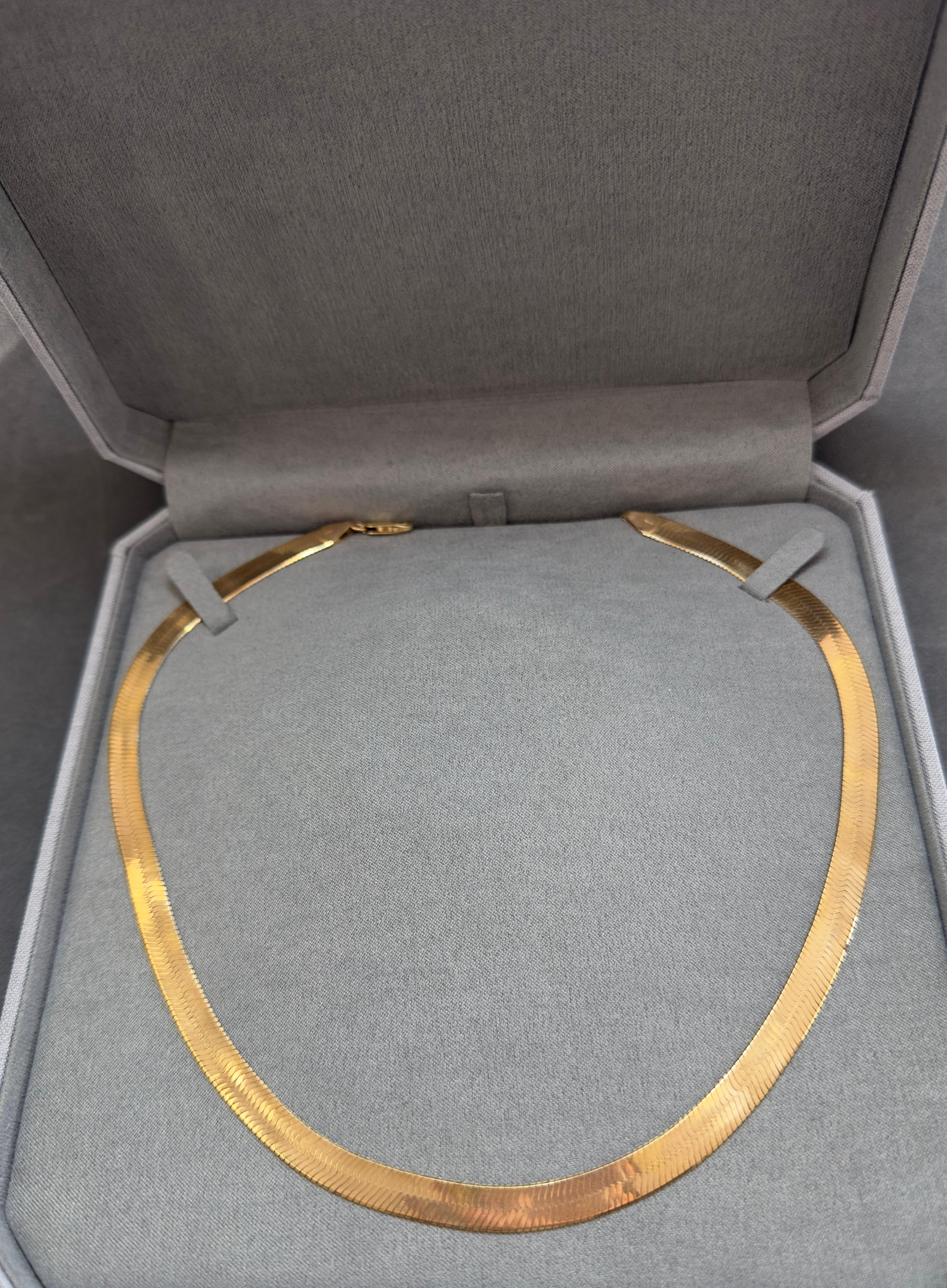 This stunning 1980s herringbone necklace is crafted in luxurious 14K yellow gold, exuding timeless elegance. With a substantial width of 7.3mm and a classic 18-inch length, it drapes beautifully along the neckline. Weighing 25.5 grams, this vintage