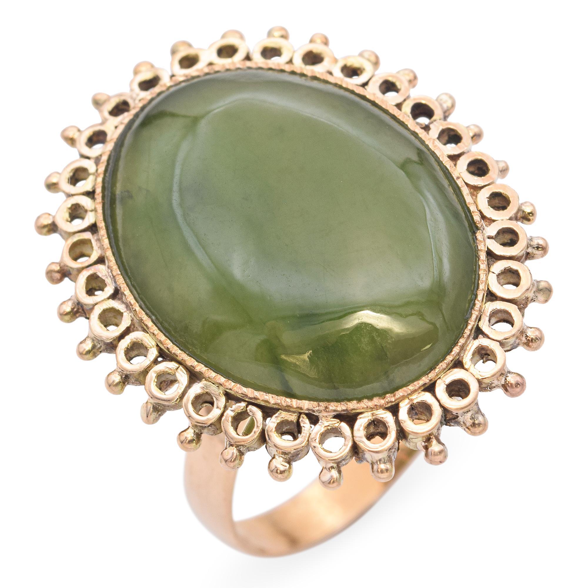 Cette bague exquise est ornée d'une grande pierre de jade vert de forme ovale, sertie dans une monture en or magnifiquement détaillée. Le cadre est orné de motifs circulaires complexes, ajoutant une touche de sophistication. La riche teinte verte du