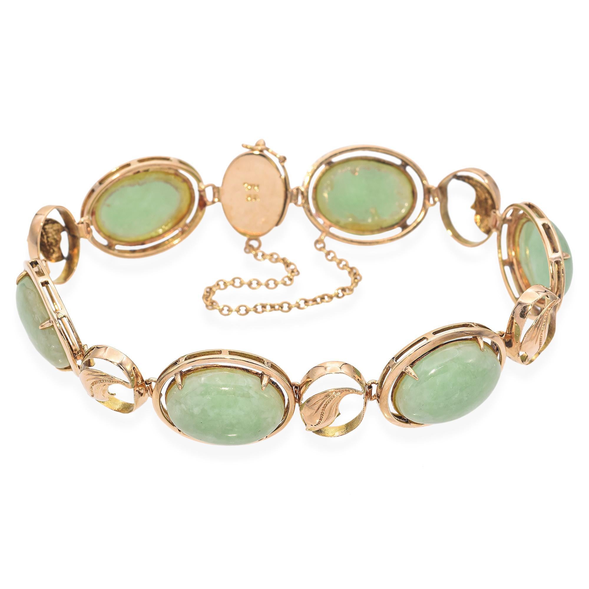 This exquisite bracelet from Hong Kong features cabochon-cut green jade stones set in 14k yellow gold, forming a series of elegant oval links. Interspersed between the jade stones are delicate gold leaf motifs. A safety chain is also included,