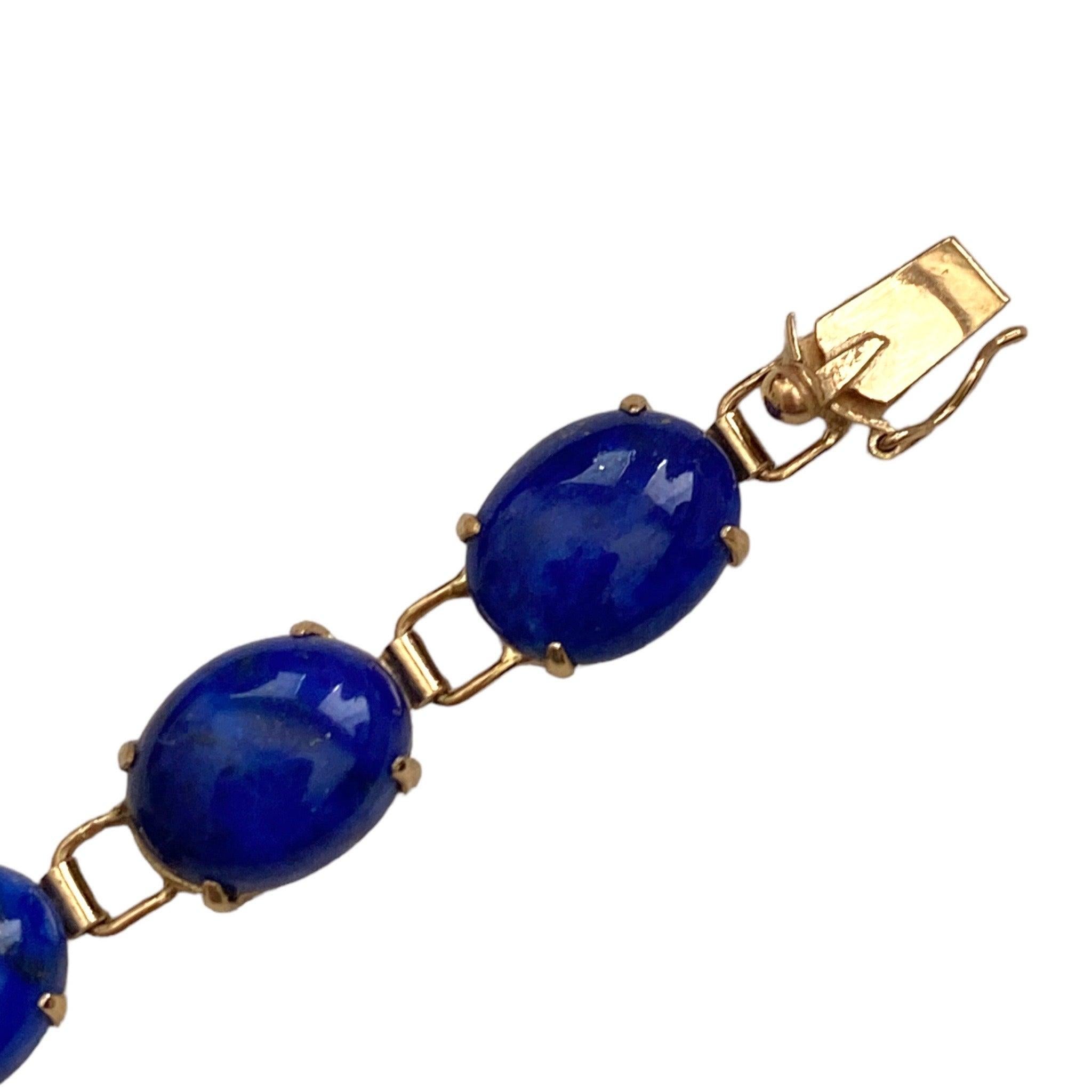 Crafted in 14K yellow gold, the bracelet is composed of fourteen in-line oval cabochon cut lapis lazuli solitaires. Each stone measures an average of 10mm x 8mm. 
Measurements:
Length: 7.25 inches
Width: 8 mm
Weight: 10.8 grams
Marked: 14K 585