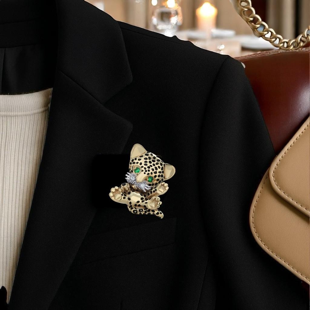 A rare and captivating find, this vintage Leopard or Cheetah Cub brooch-pendant is exquisitely crafted in 14K yellow gold, showcasing a luxurious satin finish that highlights its sculptural form. The feline is accented with striking black enamel
