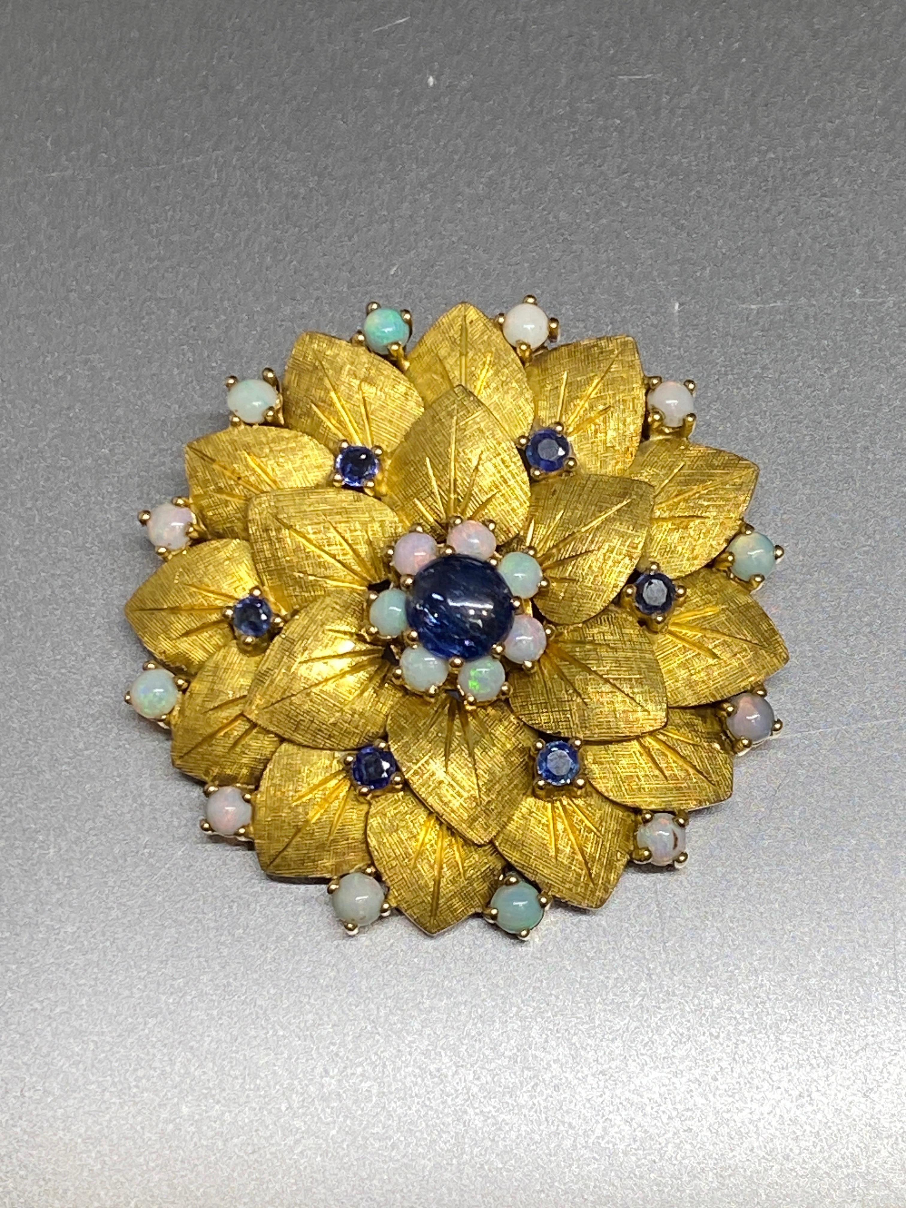 Fine 14k yellow gold, blue sapphire and opal flower brooch.  Gorgeous color combination of lustrous yellow gold rich blue sapphire and the play of color of the pastel opals.  

Two rows of artfully modeled petals with a beautiful florentine textured