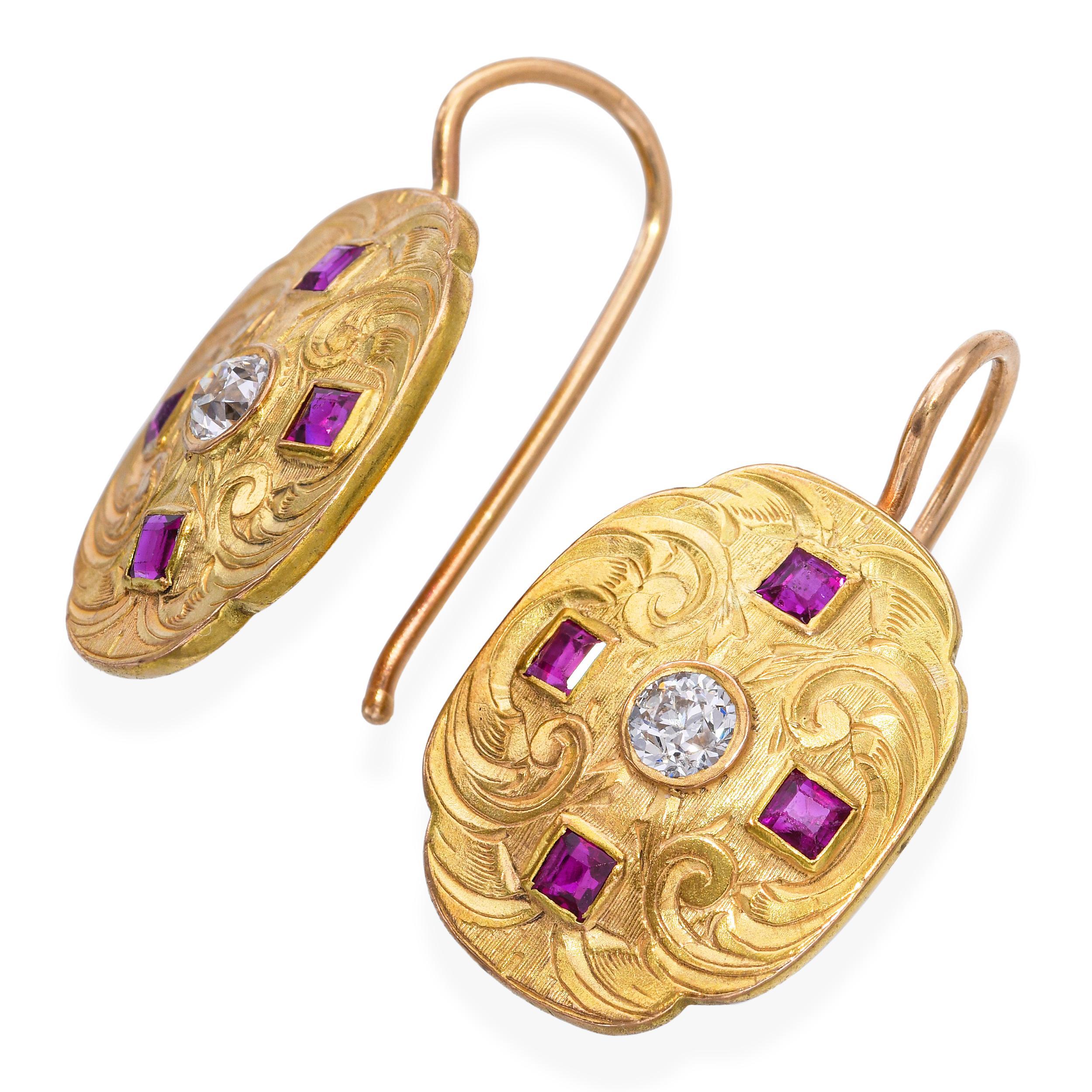 Paire de boucles d'oreilles vintage en or jaune 14k à motif de bouclier, serties de 0.22tcw de diamants étincelants et accentuées par des rubis vifs. Le bouclier décoratif présente un travail d'orfèvrerie complexe, les pierres précieuses apportant