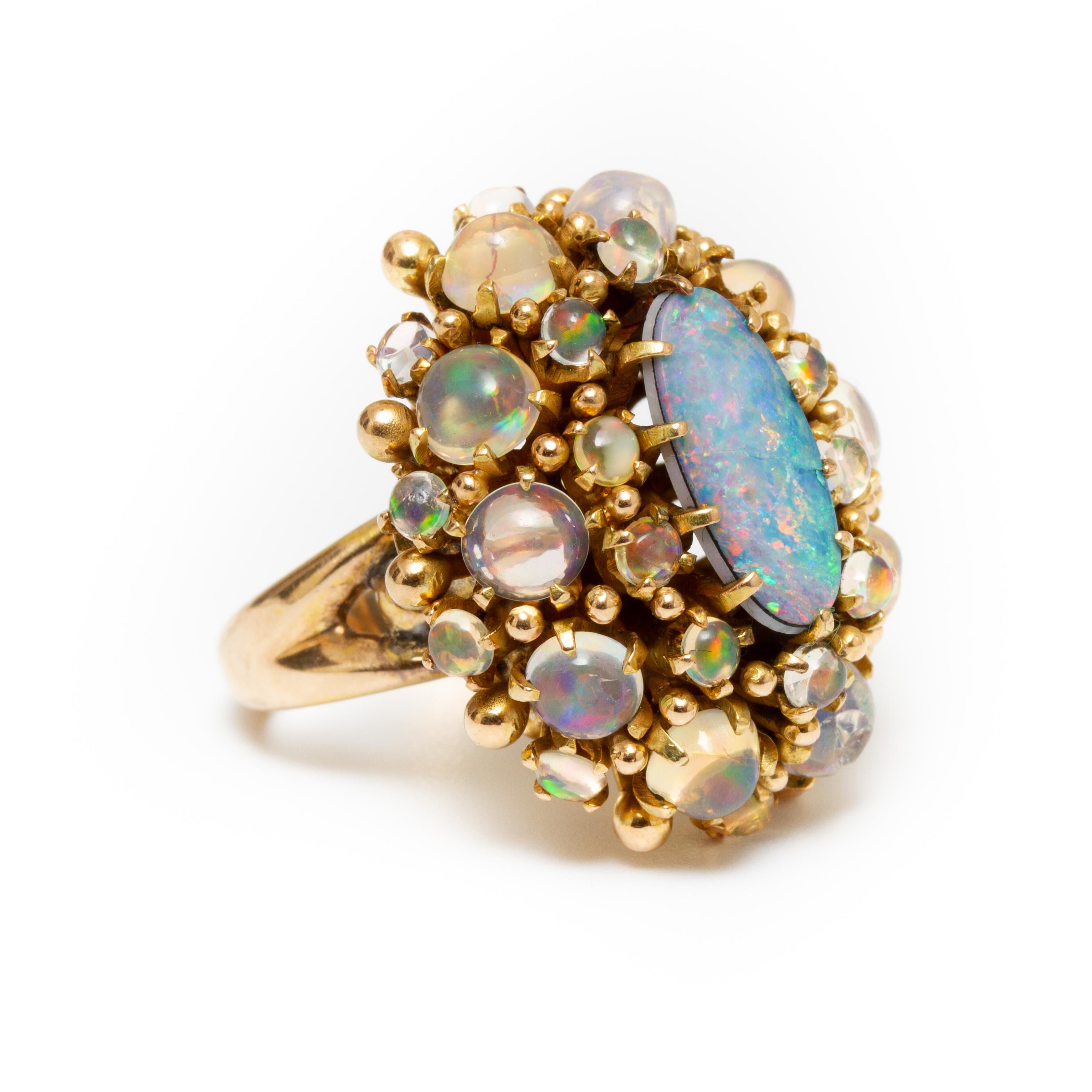 Offered is a Vintage 14K Yellow Gold Opal Triplet Cabochon Ring Surrounded by smaller opals. There are 29 Stones in total. It weighs a total of 14.60 dwt and is a size 6.