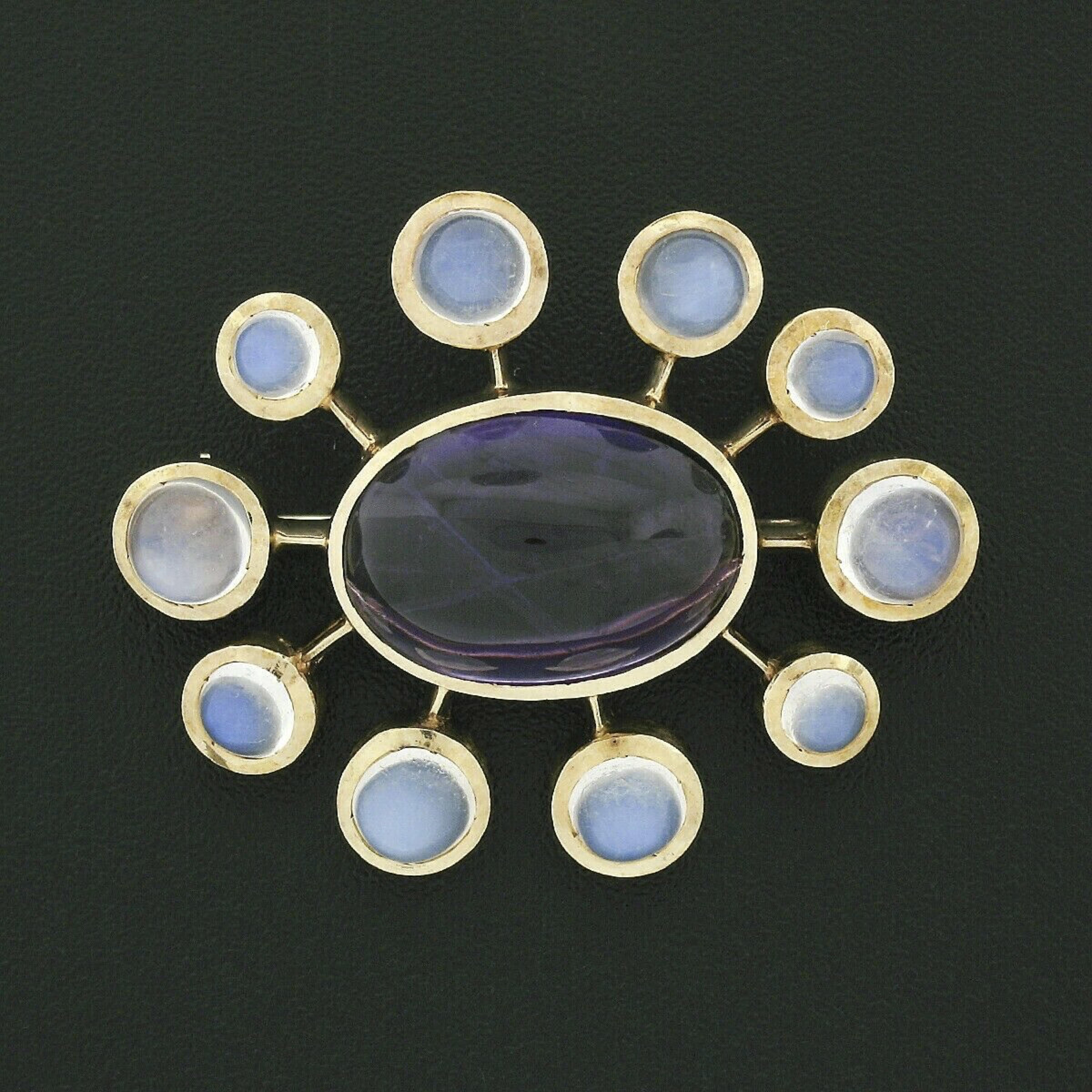 This is a truly gorgeous vintage pin brooch crafted in solid 14k yellow gold that features a nice bold design. It carries a fine quality amethyst neatly set at the center surrounded by moonstones that show variation in size throughout. The amethyst