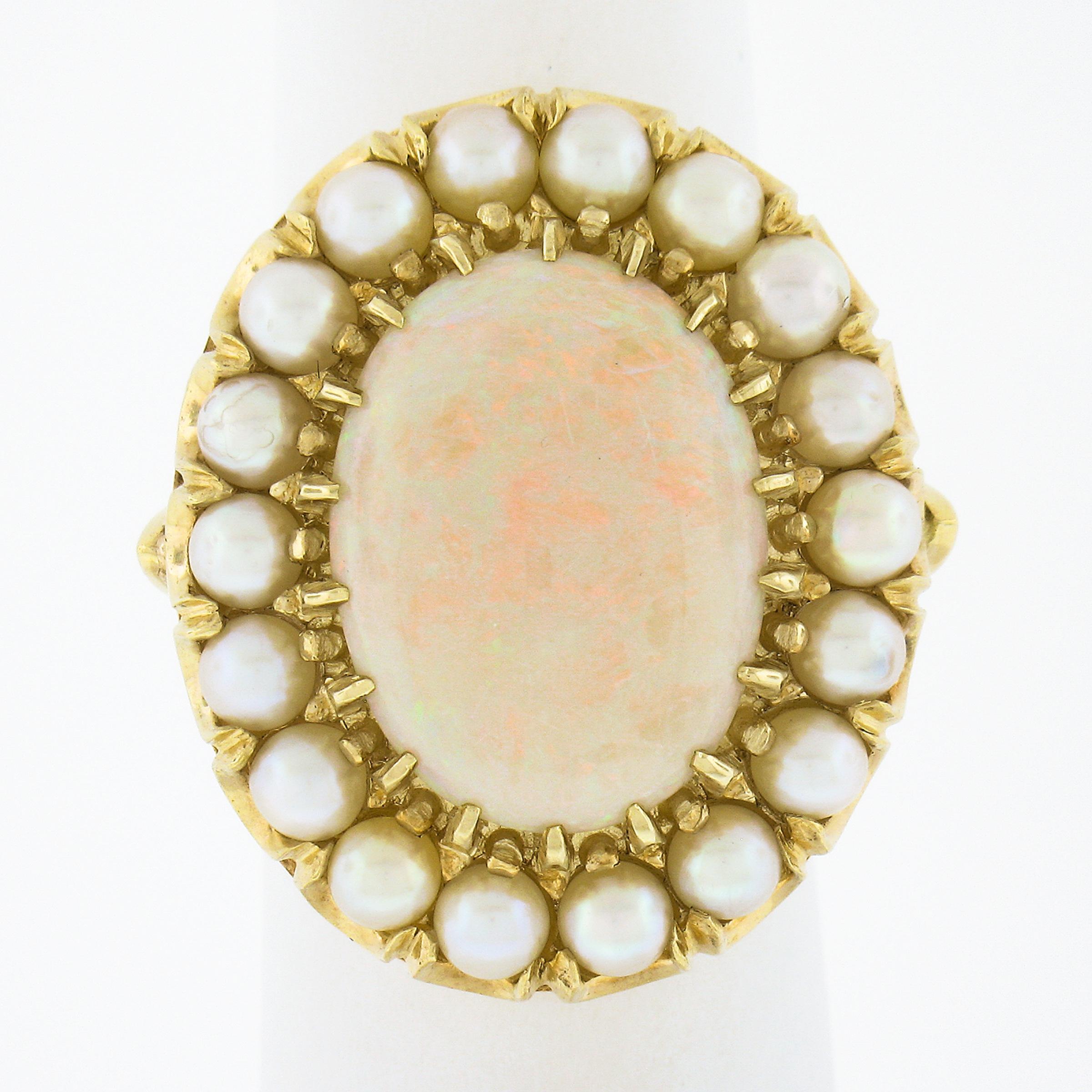 This gorgeous well made vintage ring is crafted in solid 14k yellow gold and features a stunning oval cabochon opal stone having a white base color and displays a light green and orange play throughout. The center stone is surrounded by a halo of 18