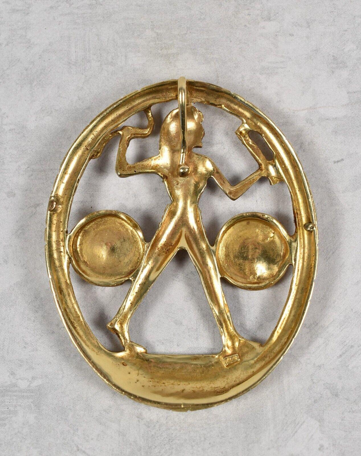 Réalisé en or jaune 14k, ce pendentif ovale représente un chasseur de l'Égypte ancienne au centre. L'anneau extérieur du pendentif présente des détails thématiques ainsi que deux cercles de part et d'autre du chasseur avec divers symboles sculptés.