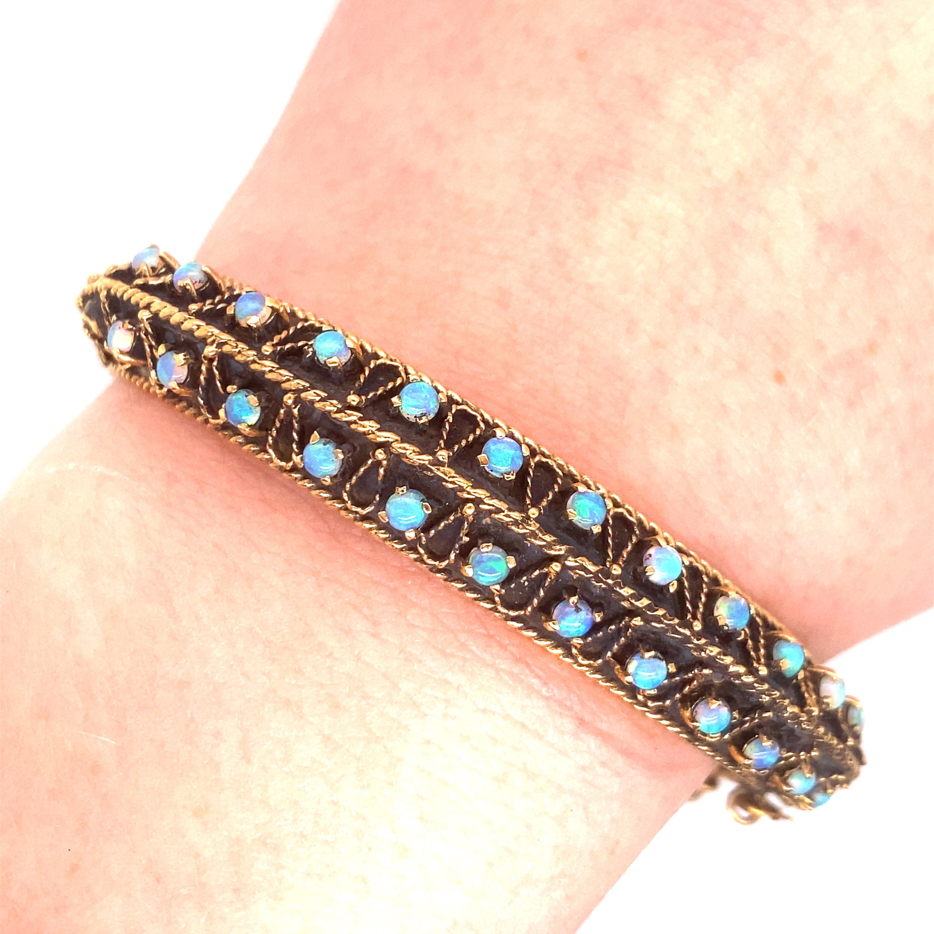 Vintage Bracelet en or jaune 14K oxydé avec Opale - Le bracelet contient 28 opales rondes avec des jeux de couleurs bleues et vertes. La largeur du bracelet est de 0,50 pouce. Le diamètre intérieur est de 2 pouces de haut par 2,25 pouces de large.