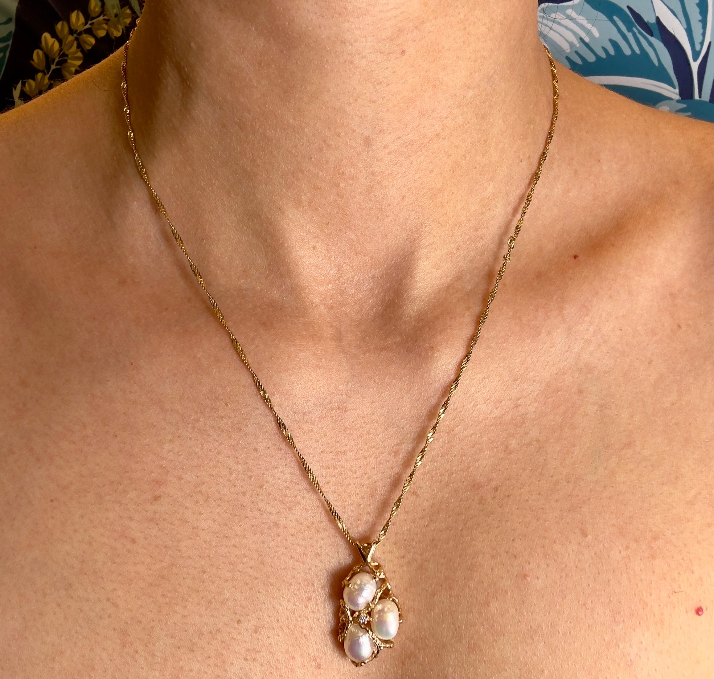 This unique vintage pendant from the 1980s showcases three lustrous pearls and one round brilliant diamond, approximately 0.03 carats, elegantly set in 14K yellow gold. Measuring 1.5 inches in height, the pendant exudes a bold yet refined charm. It