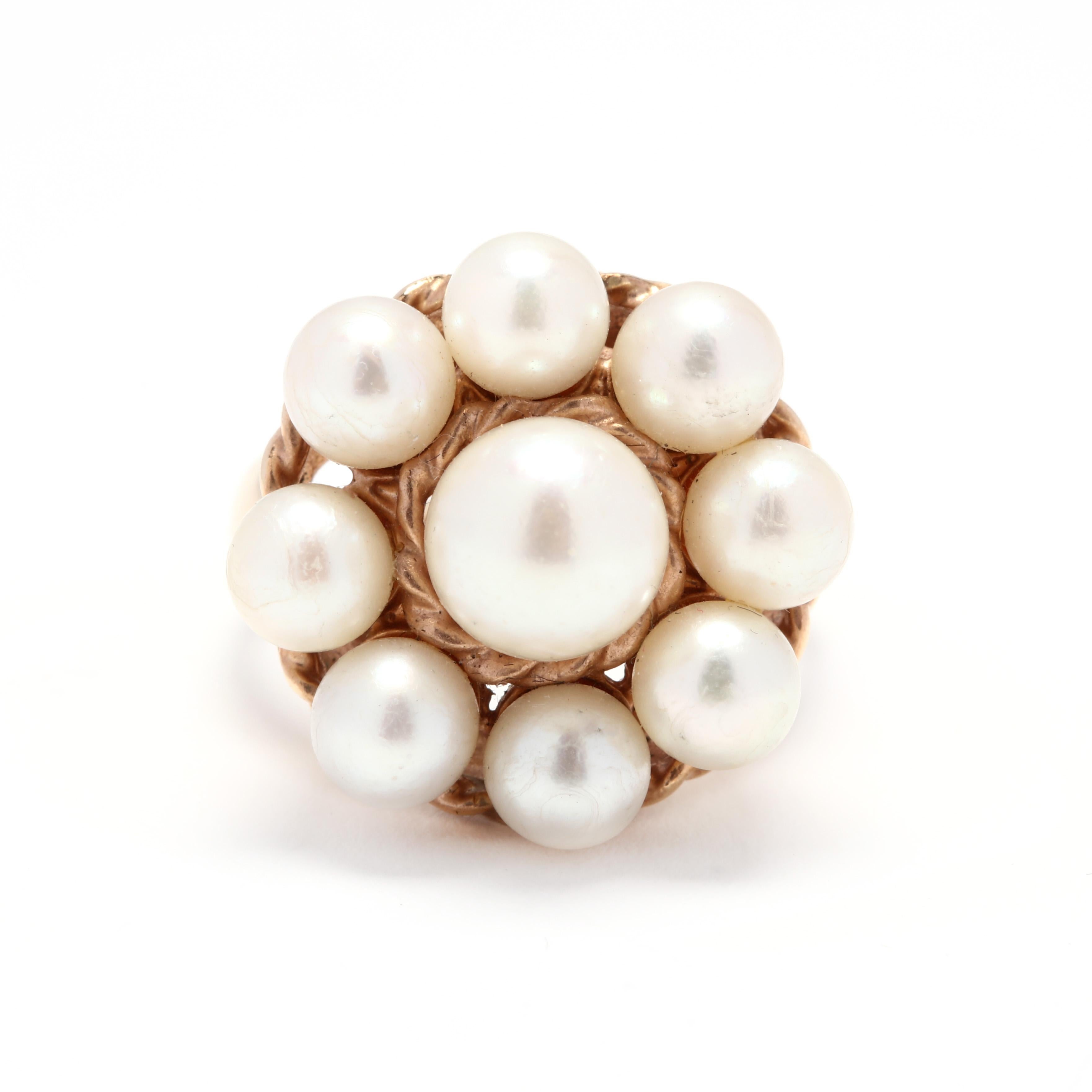 A vintage 14 karat yellow gold pearl cluster ring. A circular pearl cluster ring surrounded by a twisted gold border and with a tapered shank.

Stone:
- pearls, 9 stones
- round bead
- 5.4 - 7.5 mm

Ring Size 7.25

Width 19.6 mm

5.62 dwts

* Please