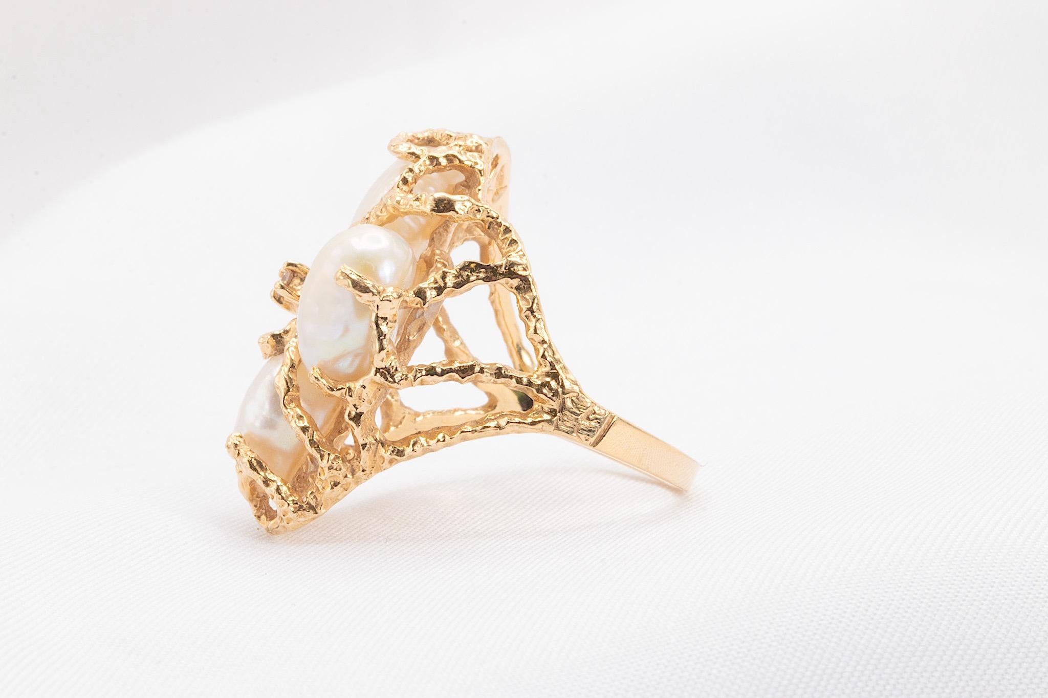 This vintage 14K yellow gold ring from the 1980s features a distinctive design, showcasing three lustrous pearls and a small round brilliant center diamond of approximately 0.03 carats. Weighing 6.8 grams, this beautifully crafted piece combines