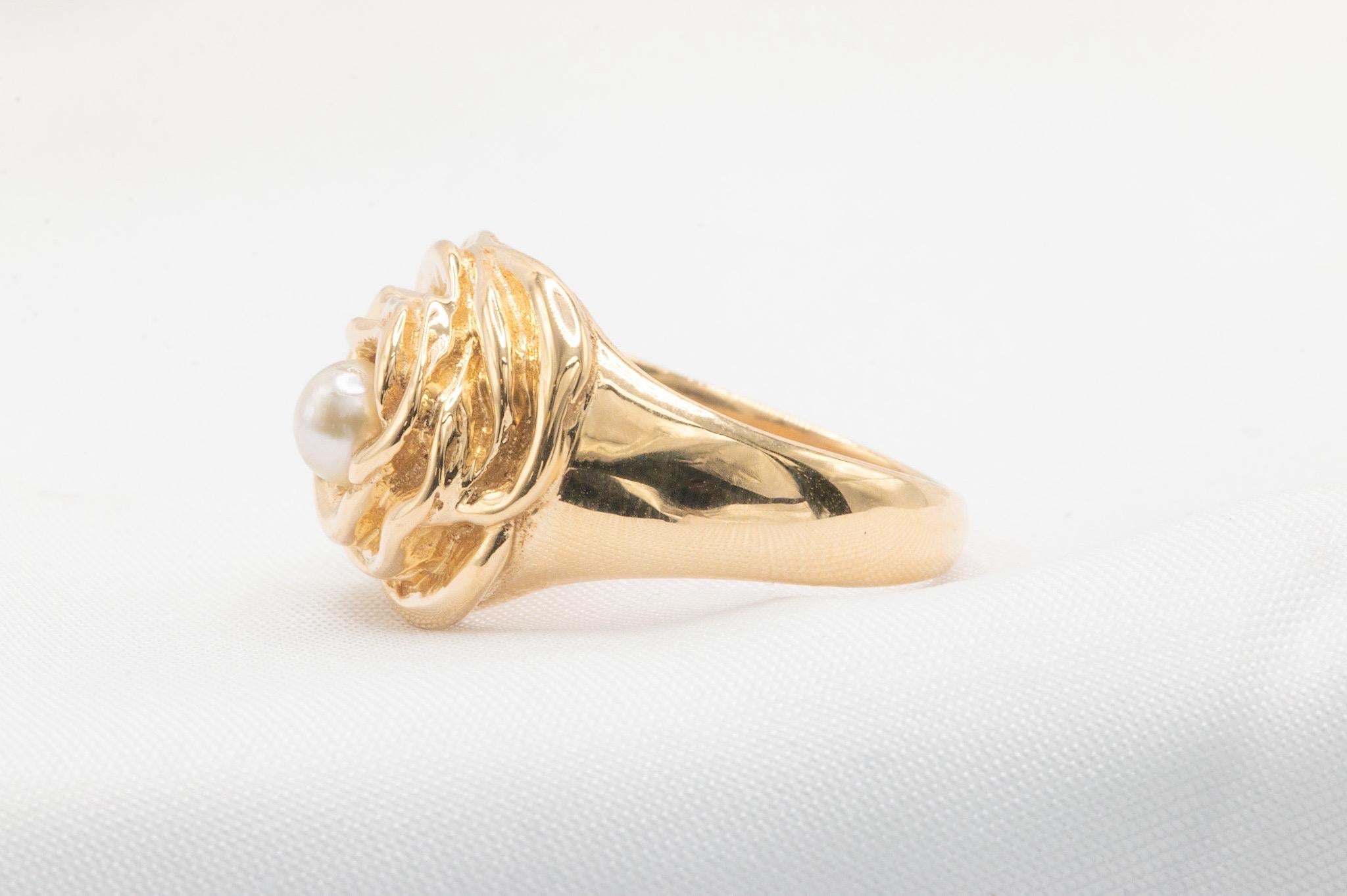 Questo anello vintage in oro giallo 14K degli anni '80 sfoggia un design floreale senza tempo, centrato da una singola perla rotonda per un look elegante e unico. Con un peso di 8,40 grammi, questo pezzo di ottima fattura cattura il fascino vintage