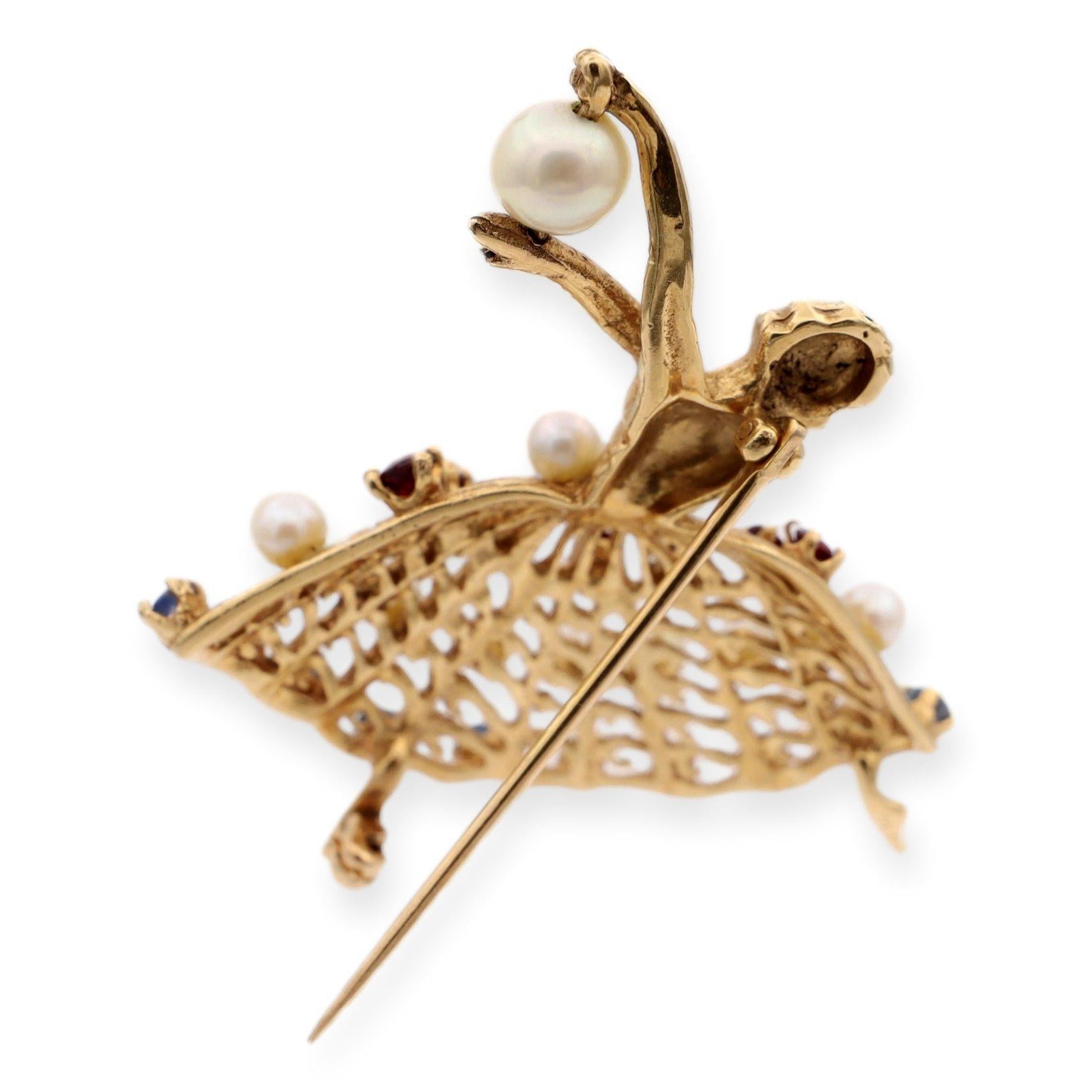 Vintage Ballerina Brooch finely crafted in 14 karat yellow gold. Its exquisite detailing showcases a graceful ballerina figure, capturing the elegance and charm of classical ballet. Adorned with a stunning combination of rubies, blue topaz, and
