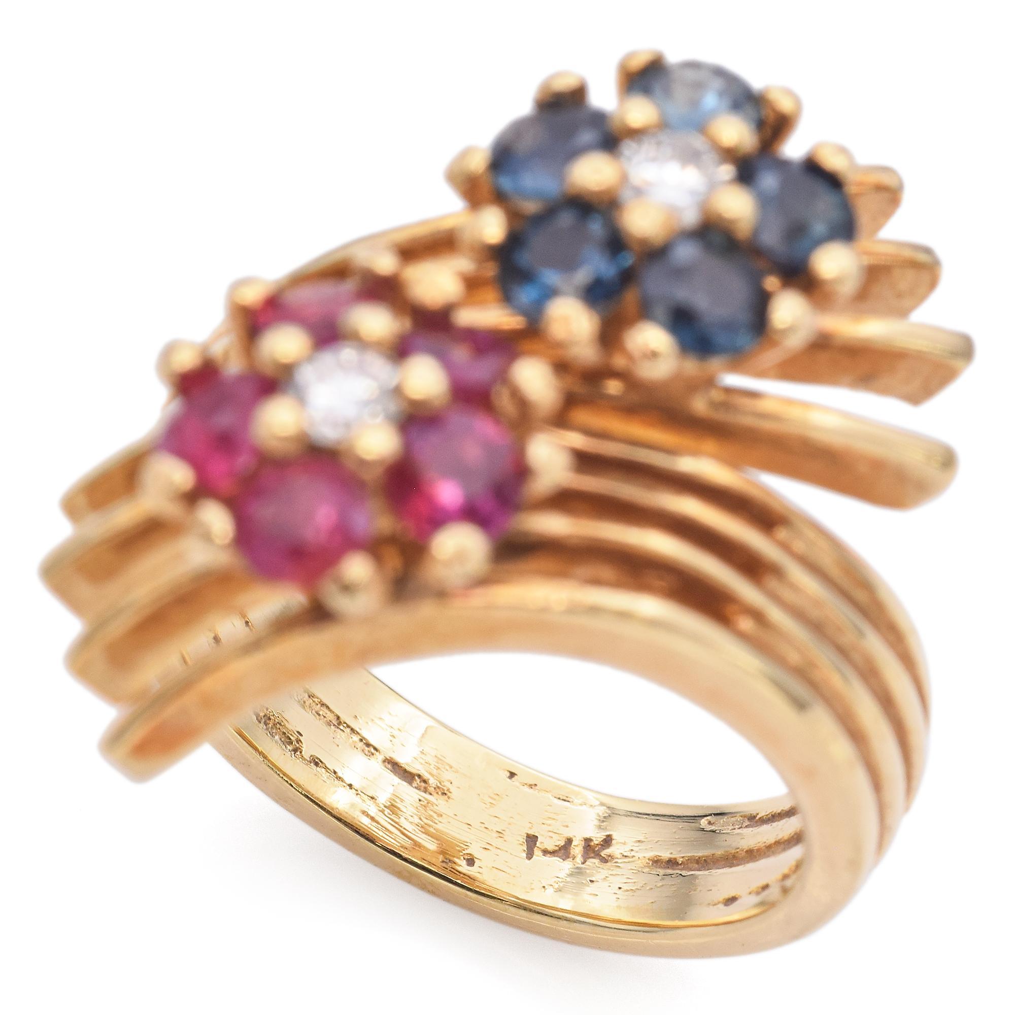 This exquisite ring features a vibrant arrangement of round-cut stones. The primary stones are rich red rubies, weighing 0.45 carats, complemented by deep blue sapphires totaling 0.47 carats. Each cluster is centered with a sparkling diamond, adding