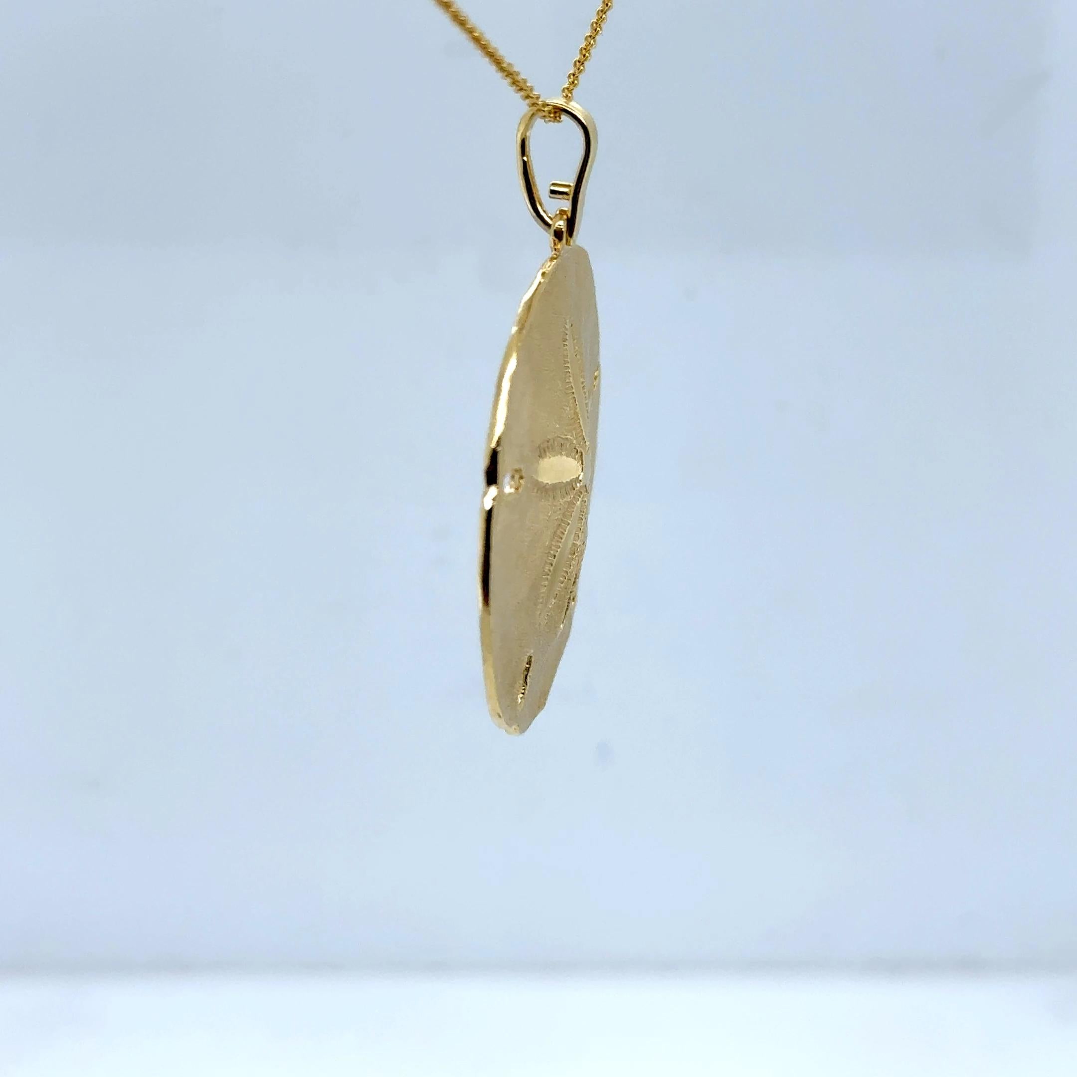 Ce pendentif vintage en forme de dollar des sables est réalisé en or jaune 14 carats massif, offrant un ton riche et chaud et un toucher substantiel qui capture l'essence des bijoux de luxe d'inspiration côtière. Mesurant 1,50 pouce de long, y