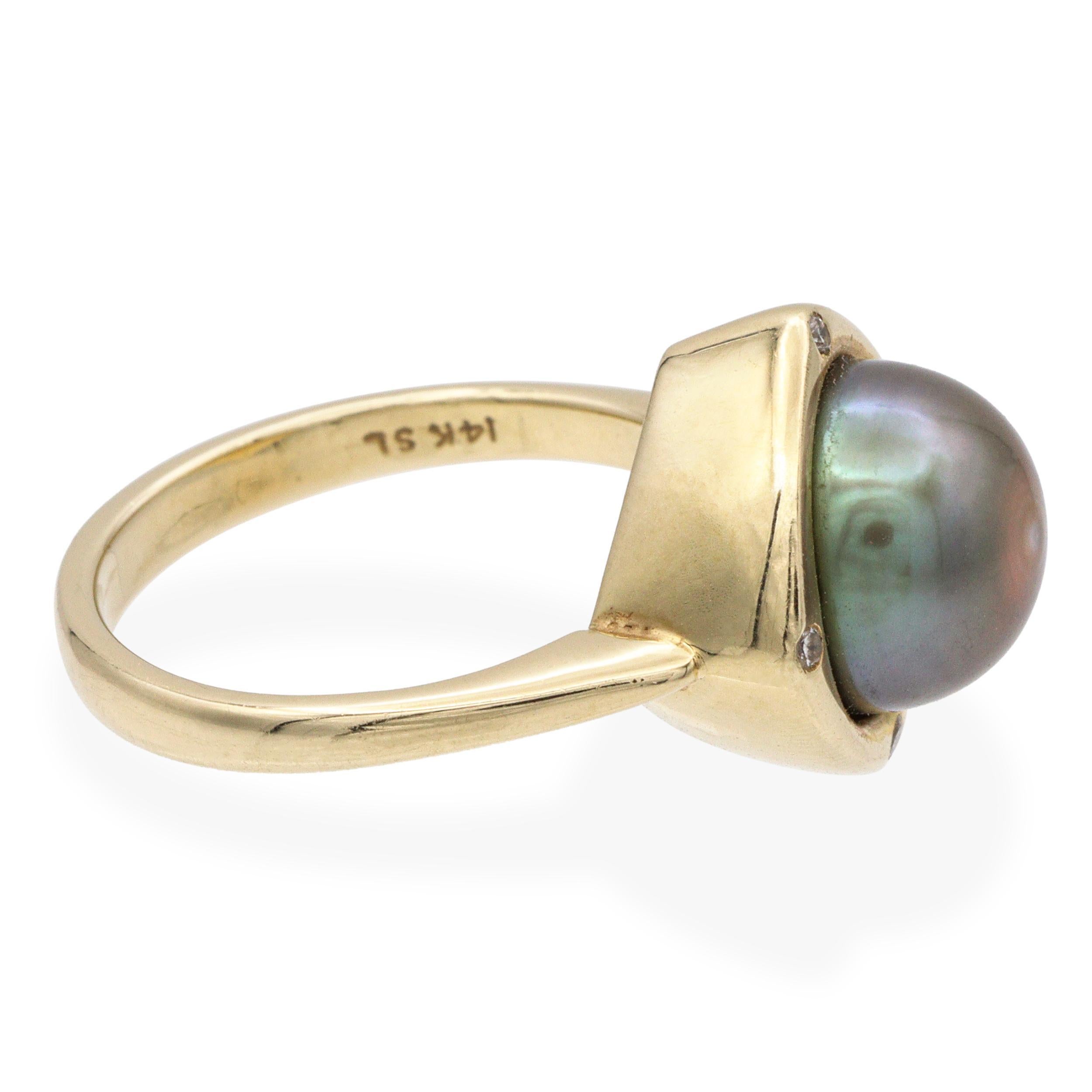 Este anillo vintage de oro amarillo de 14k presenta una lustrosa perla de Tahití en el centro, elegantemente flanqueada por brillantes detalles de diamantes. Los ricos tonos oscuros de la perla contrastan maravillosamente con el cálido oro y los
