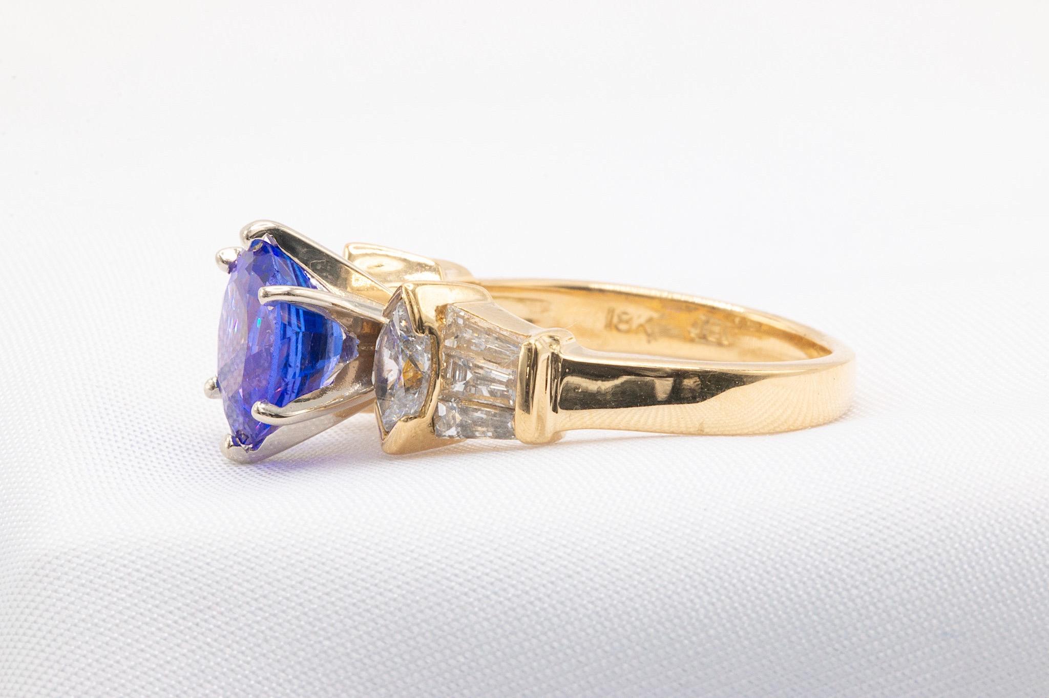 This beautiful vintage ring from the 1980s features a captivating 2-carat oval tanzanite, paired with sparkling marquise and baguette diamonds totaling approximately 1 carat (F-G color, VS clarity). The vibrant tanzanite and shimmering diamonds are