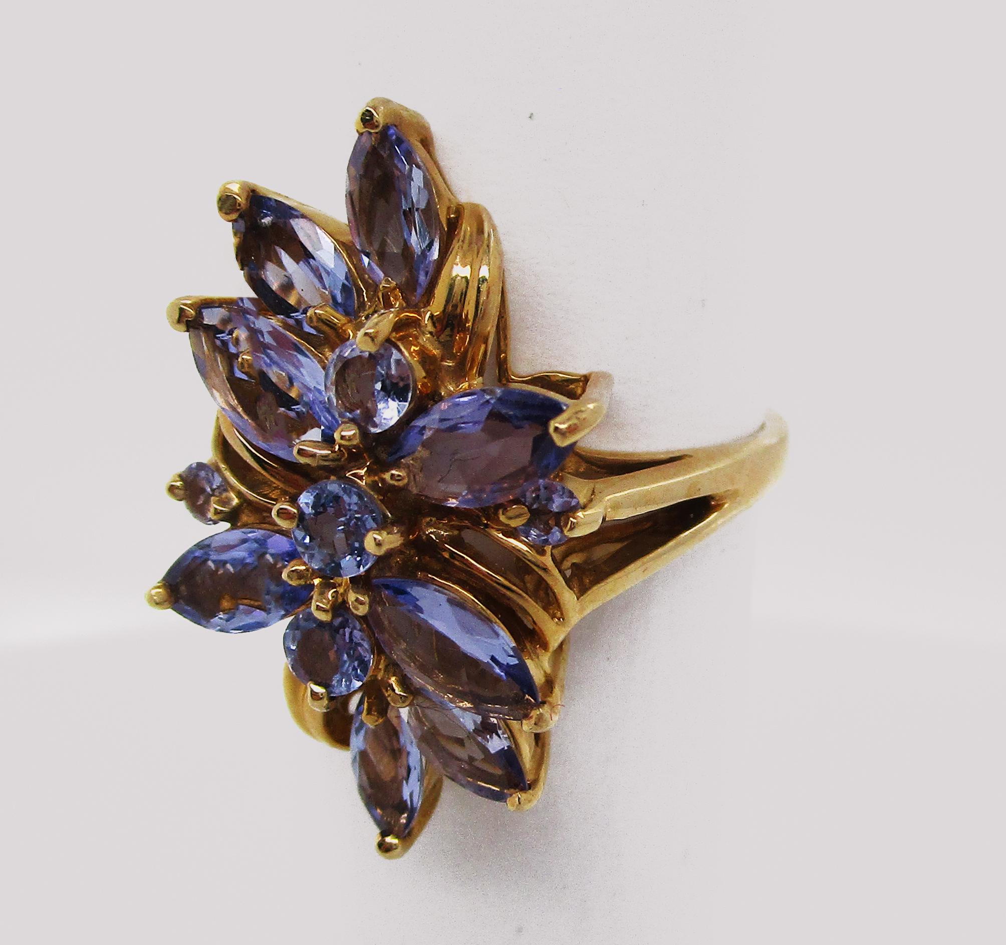 This is a fantastic ring in 14k yellow gold featuring a lovely array of tanzanite in an elegant waterfall design! The under gallery has an architectural look to it, making the ring light and sit excellently on the hand. The center of the ring