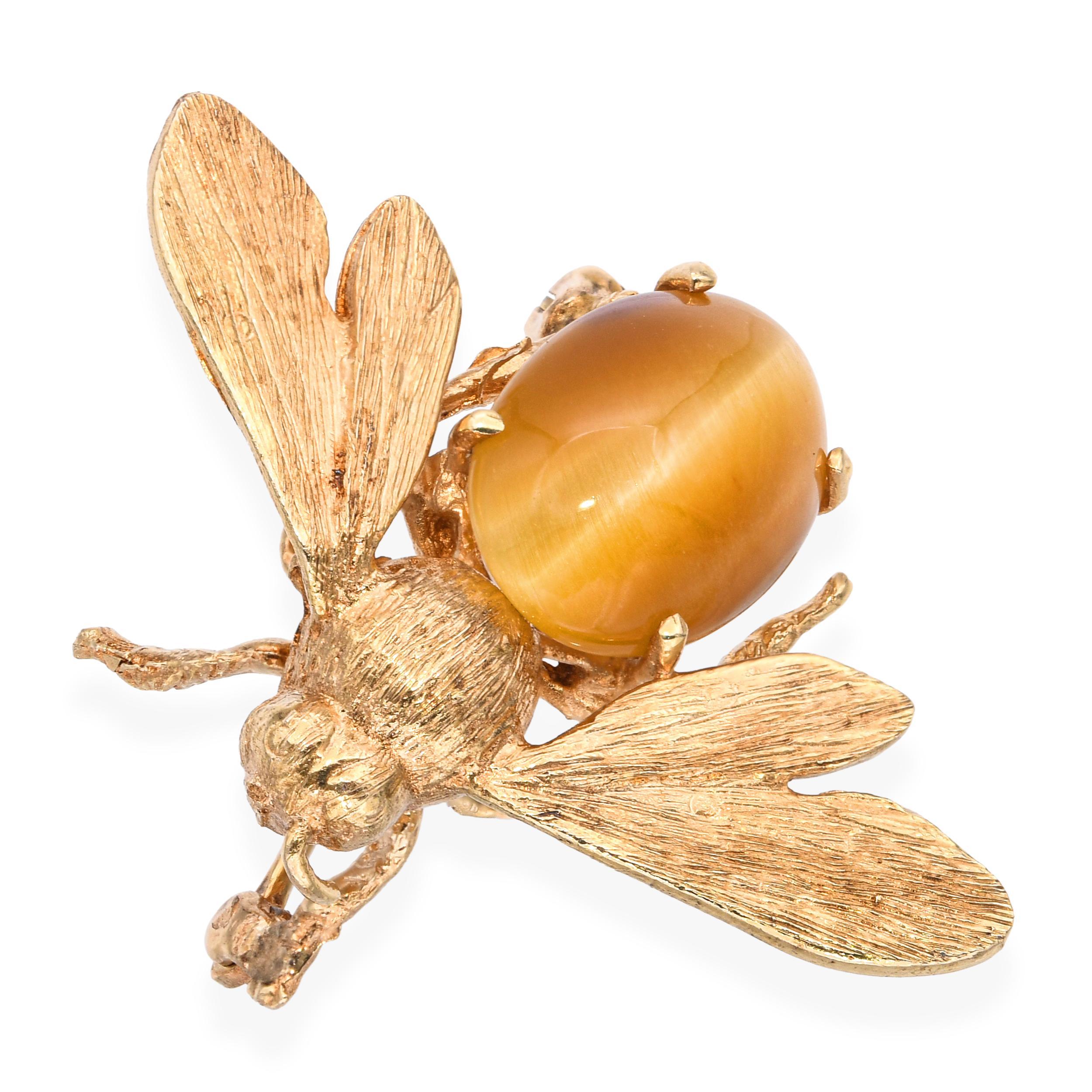 This charming vintage brooch is crafted in 14k yellow gold and designed in the whimsical form of a bumblebee. The body is set with polished tiger’s eye, showcasing its warm golden-brown chatoyancy that mimics the natural stripes of a bee. Fine gold