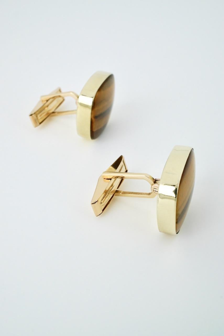 A vintage pair of 14k yellow gold and tigers eye cufflinks - Karram - a rounded rectangular tablet of tigers eye bezel set in gold with a hinged lever back - these beautiful cufflinks with their subtle colours of gold and minimalist settings really