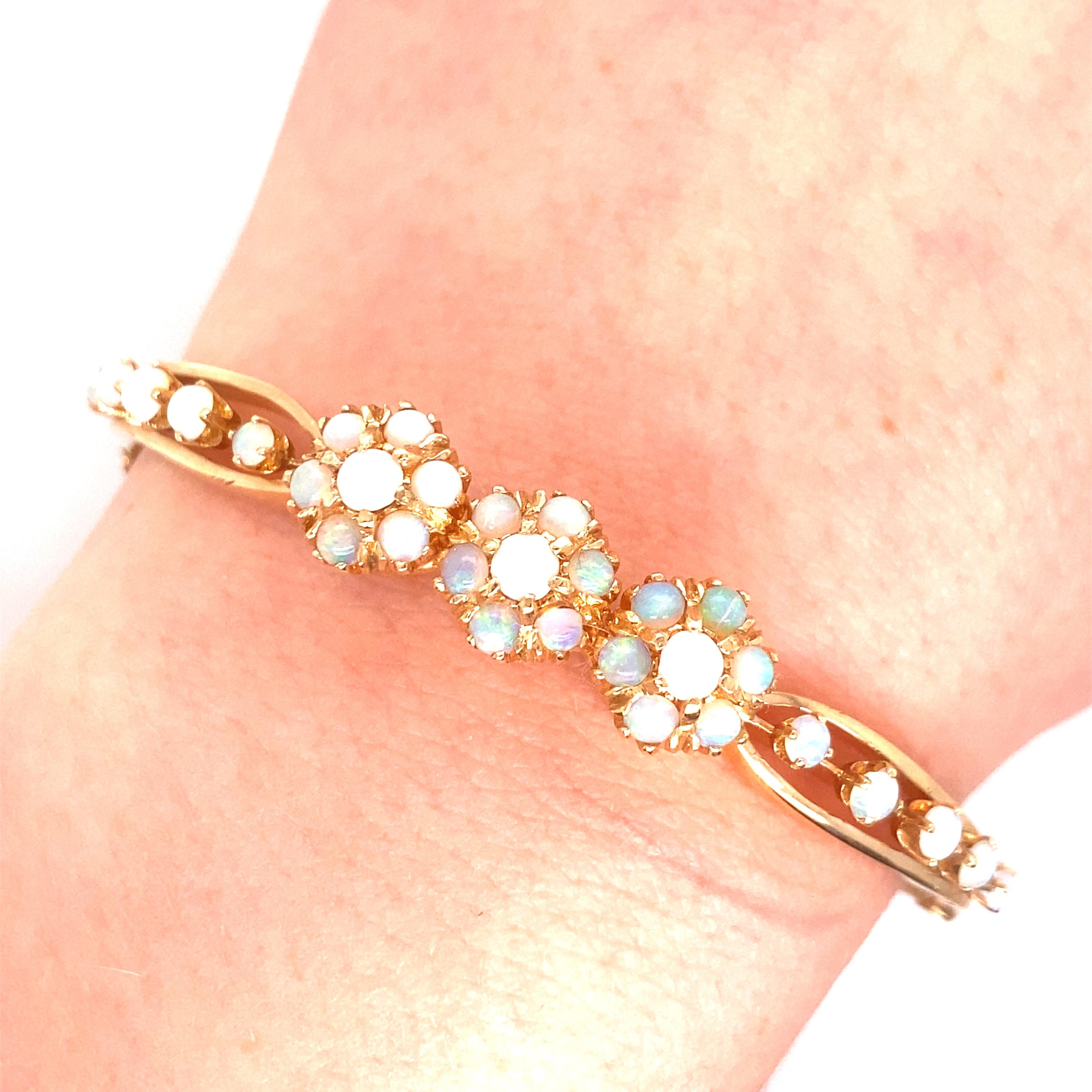 Vintage 14K Yellow Gold Victorian Reproduction Opal Bangle - Le bracelet a 3 fleurs composées de 7 opales rondes chacune avec 5 opales supplémentaires sur chaque côté. Les opales présentent un jeu de couleurs vertes et rouges. La largeur du bracelet