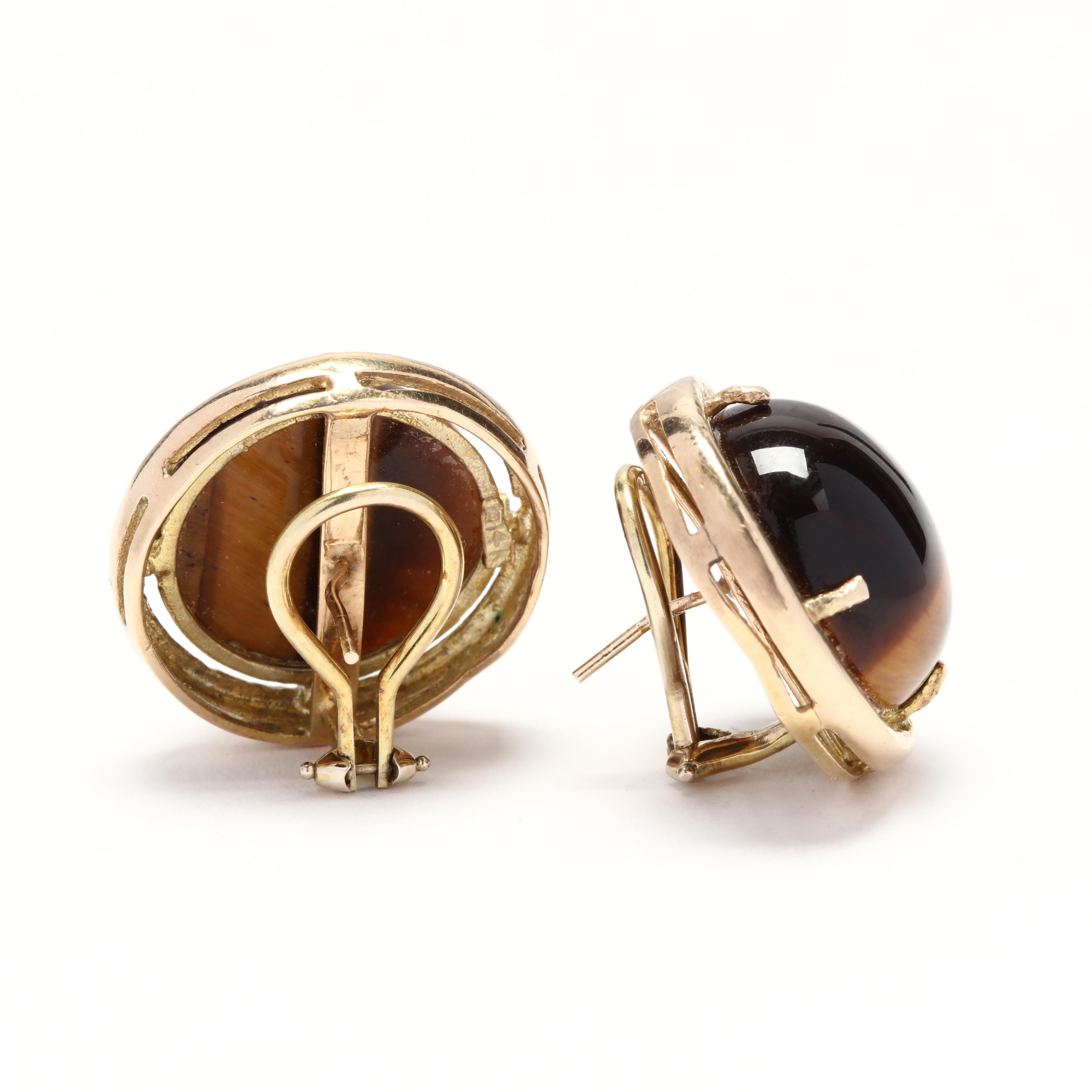 A pair of vintage prong set, round cabochon tiger's eye earrings with a gold border and pierced omega backs.

Stones:
- tiger's eye, 2 stones
- round cabochon
- 18 x 18 x 7.25 mm

Length 23.5 mm

10.91 dwts.

* Please note that this is a vintage