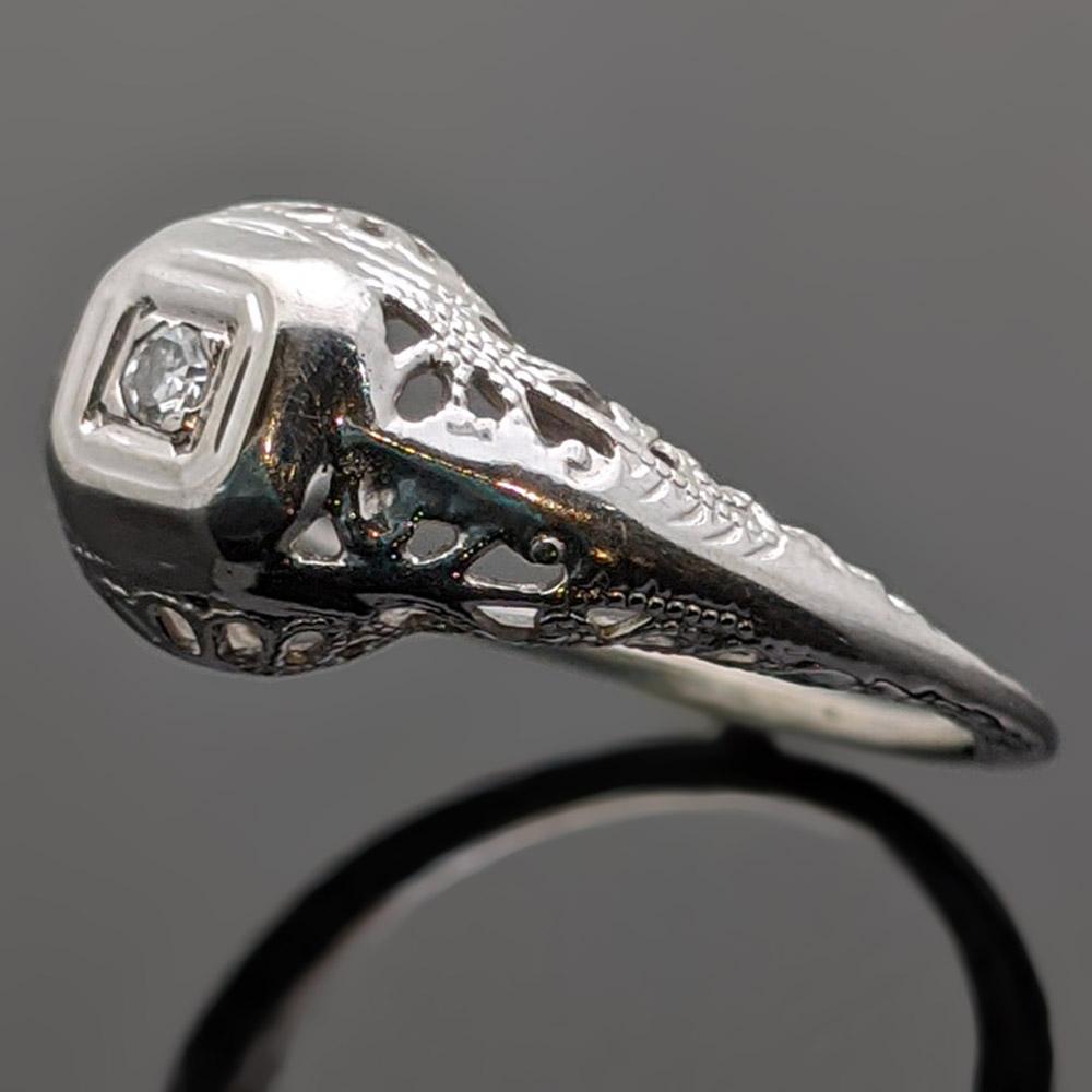 Intricate vintage 14kt white gold diamond art Deco ring with a one prong set diamond with an estimated weight 0.20 ct. Engraved floral motifs accent the shank. Estimated weight of gold 1.5 gr. 

We will size it for you.

