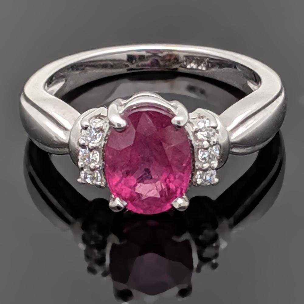 A vintage 14kt white gold, pink  sapphire and diamond ring starring an oval cut sapphire with an estimated weight of 1.84ct. in a 4 prong setting and three diamonds on each side with an estimated weight 0.06 cttw  Estimated weight of gold 2.5 gr. 