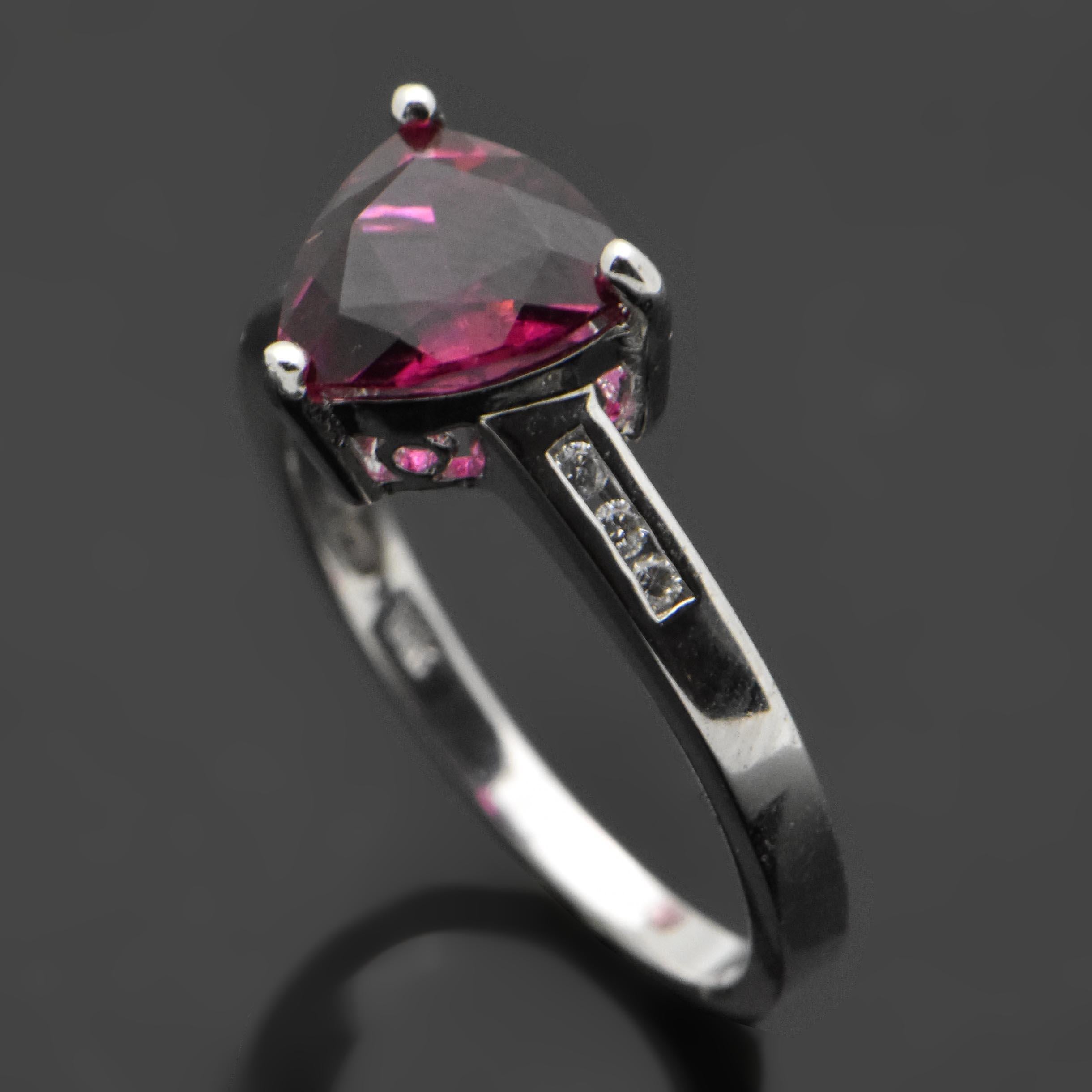 A vintage 14kt white gold ring set with a triangle-cut tourmaline at an estimated weight of 1.46 ct. and six diamonds with a 0.05 cttw. Estimated weight of gold is 2 gr. 

We will size it for you.

