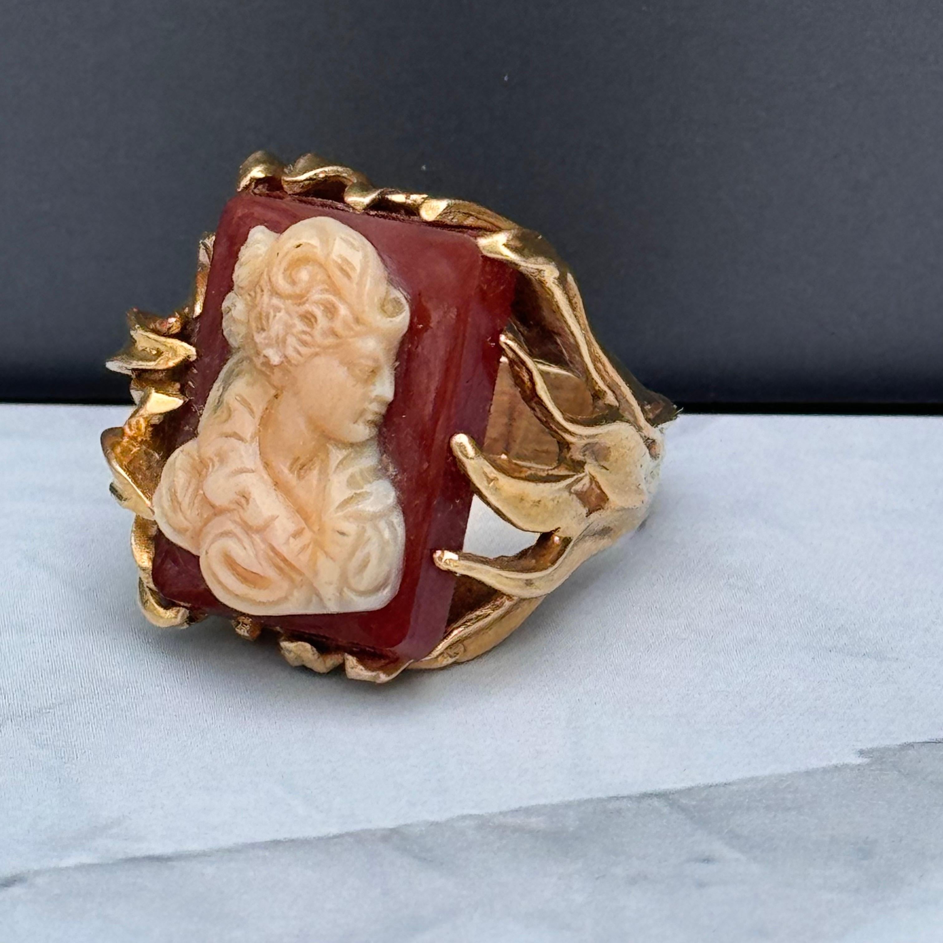 The Vintage Hard Stone Cameo Dinner Ring is an elegant piece crafted in 14kt gold, featuring a beautifully deeply carved hard stone Female Bust cameo  set on a nice organic leaf design band. Its intricate design adds a touch of sophistication,
