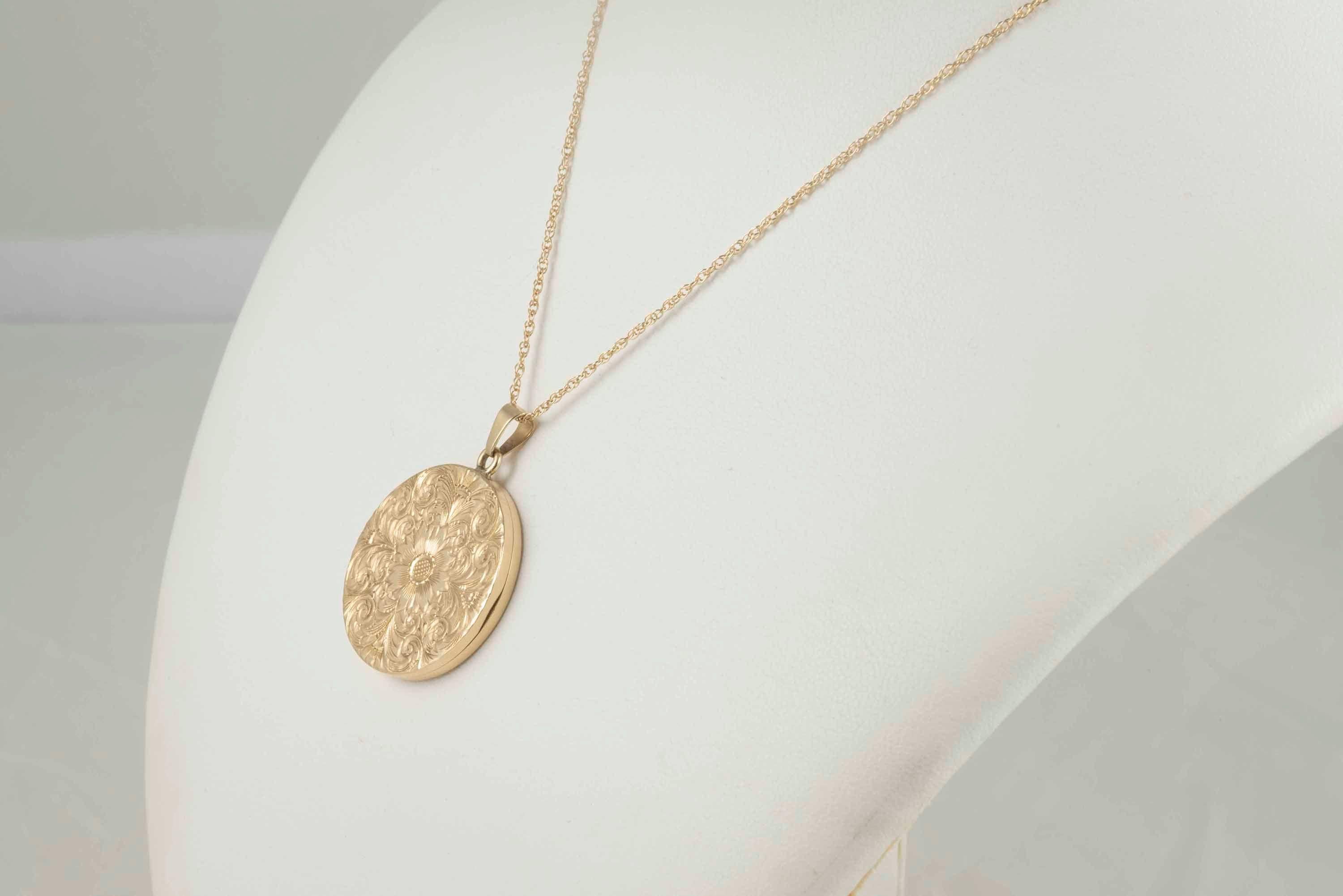 Crafted in the 1940-50s from 14kt yellow gold, this round locket measuring 1.1 inches features a beautiful hand-crafted floral engraving. 
The chain measures 17 inches long. 