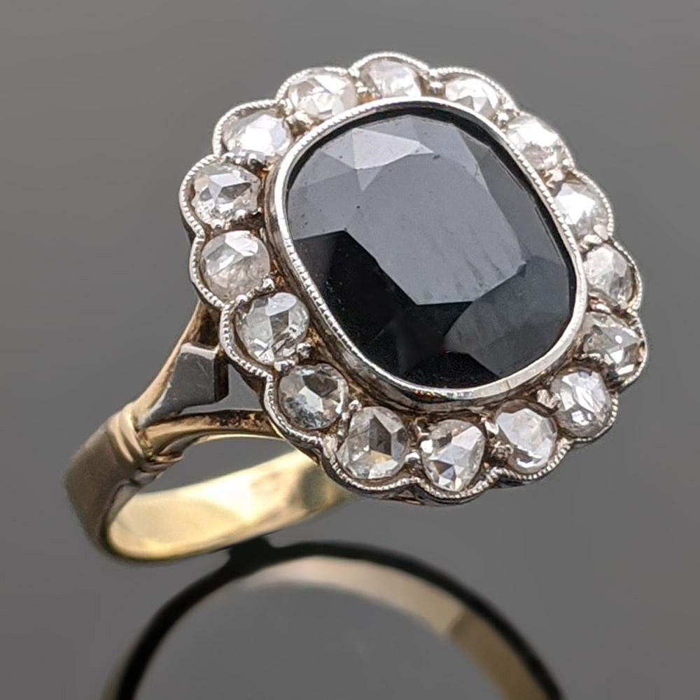 Circa 1930s vintage 14kt yellow gold and sapphire ring encompassed with diamonds. The center stone is a cushion cut sapphire in a bezel setting with an estimated weight 1.70 ct. and surrounded by 16 diamonds with an estimated 0.32 cttw. Estimated