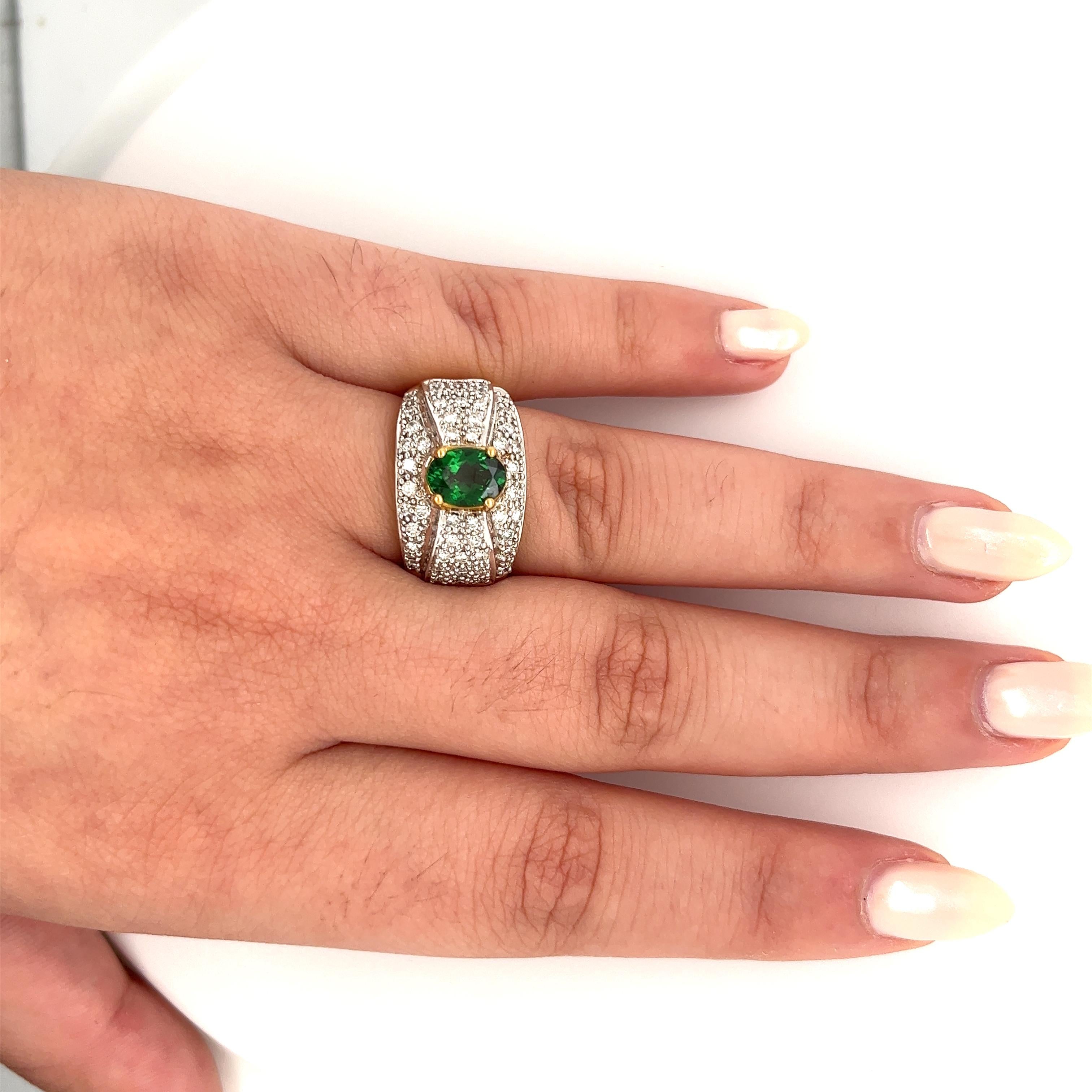 Vintage tsavorite and diamond cluster ring in 18k solid gold. Featuring a richly colored oval cut green and round cut diamond side stones. Mounting in a two-toned solid gold setting.

Tsavorite is a rare form of Garnet called Green