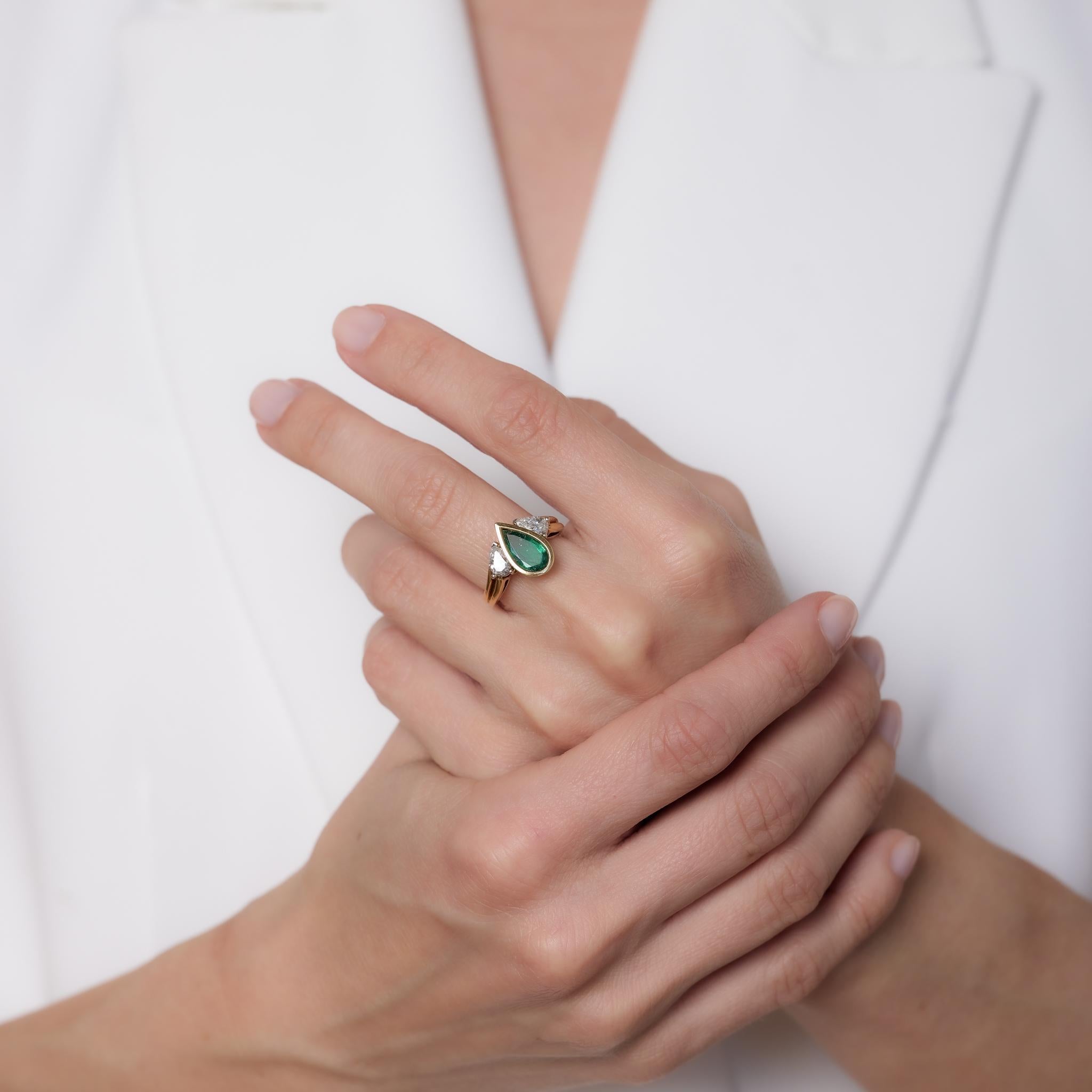 This vintage 18k yellow gold ring showcases a 1.50-carat pear cut emerald, complemented by two pear cut diamonds totaling approximately 0.45 carats, H-I color, and VS clarity. Crafted in the 1990s with platinum prongs, it is hallmarked with purity