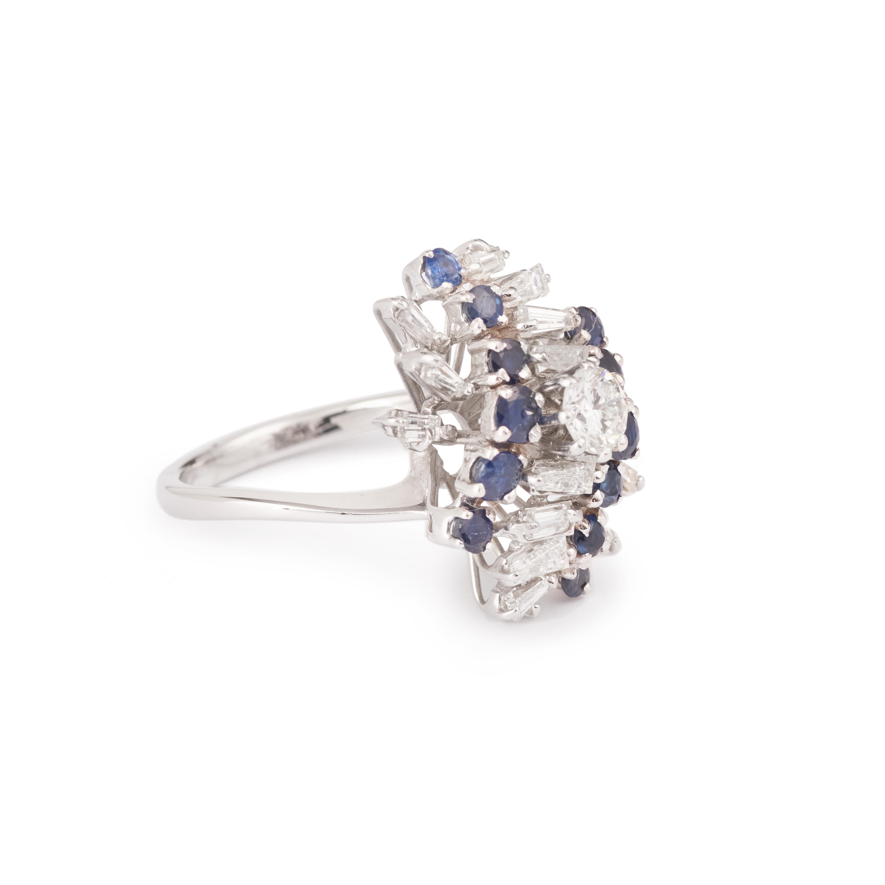 Amazing ring in white gold, adorned with a central brilliant cut diamond of 0,50 carat approximately bordered by eight trapeze diamonds and shouldered by two lines of facetted sapphires highlighted with six smaller trapeze diamonds.

Main diamond