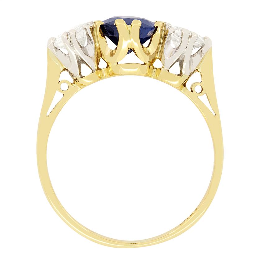 Questo anello trilogy vintage degli anni '50 ha un design elegante e senza tempo. Il centro è costituito da uno splendido zaffiro ovale da 1,50 carati, incastonato nell'oro giallo da 18 carati. Lo zaffiro è affiancato da due diamanti tondi brillanti
