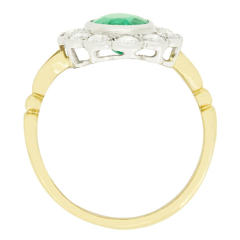 Una hermosa esmeralda verde es la protagonista de este anillo vintage en racimo. La esmeralda de talla oval pesa 1,55 quilates y está engastada en platino. Rodeando la piedra central, se engastan un total de diamantes brillantes redondos de 1.20
